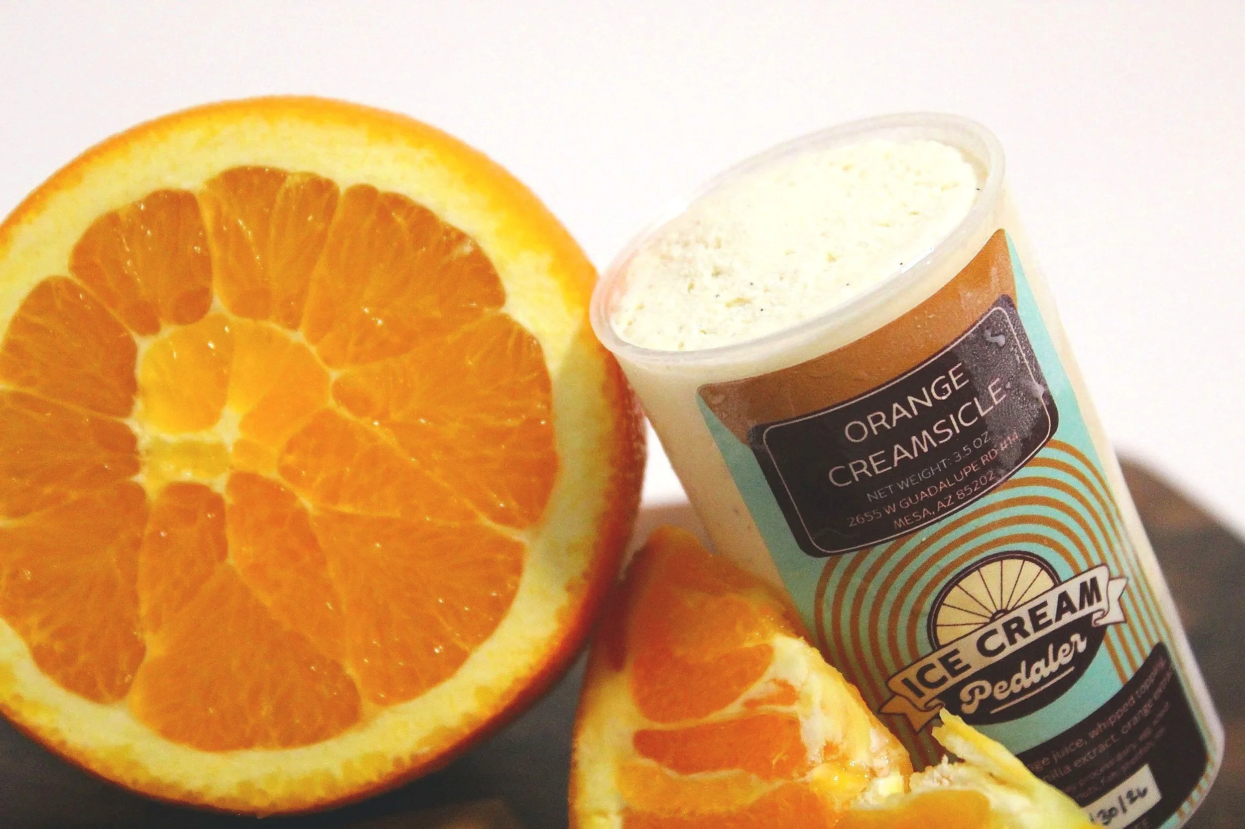 Close-up of a halved orange and a container of an orange creamsicle push pop