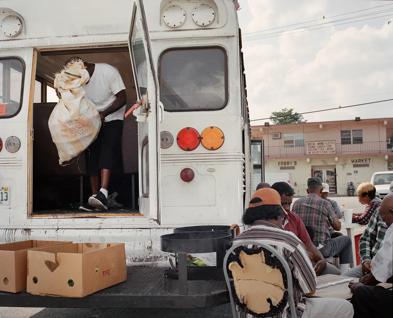 A man grabs corn from a bus that was collected by workers during a day of corn picking.