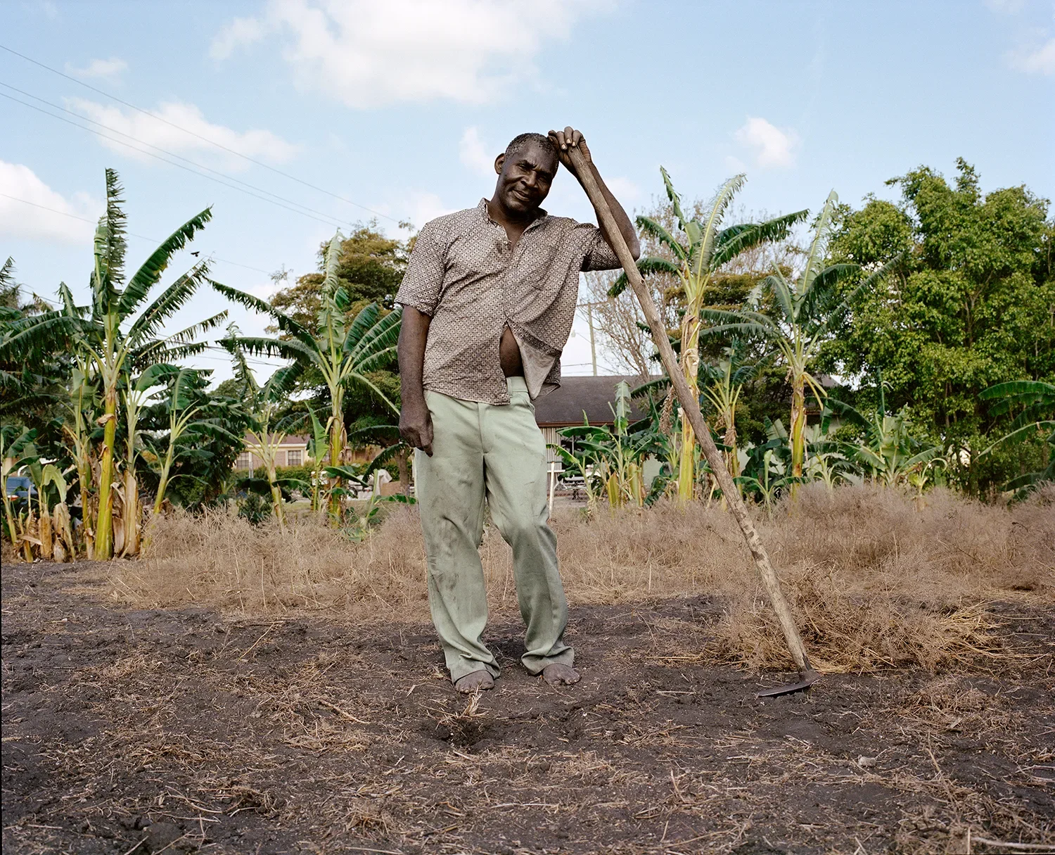 A man prepares some land for farming outside of his house.