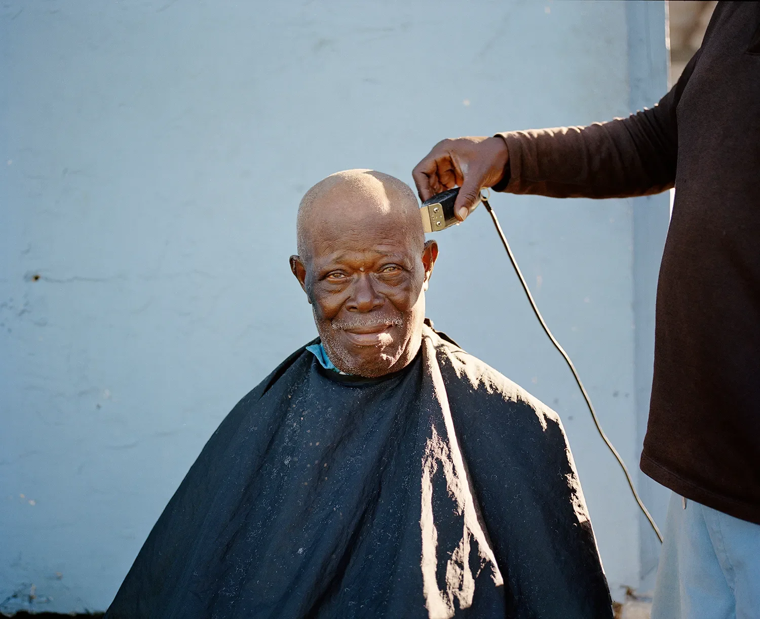 A man gets a haircut outside of his apartment in downtown Belle Glade.
