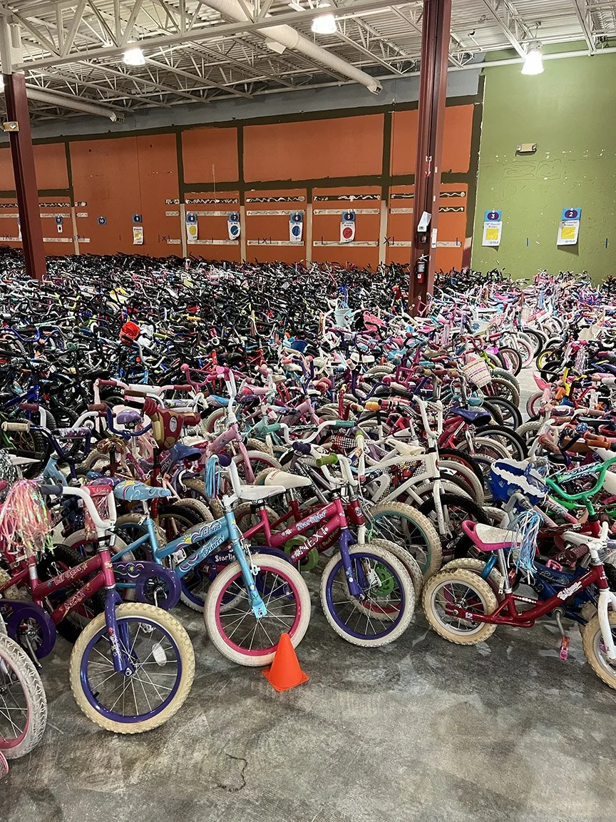 A FB4KMN donation site warehouse filled with numerous children's bicycles parked in rows, with colorful bikes what will be cleaned, refurbished and then donated to children in need.