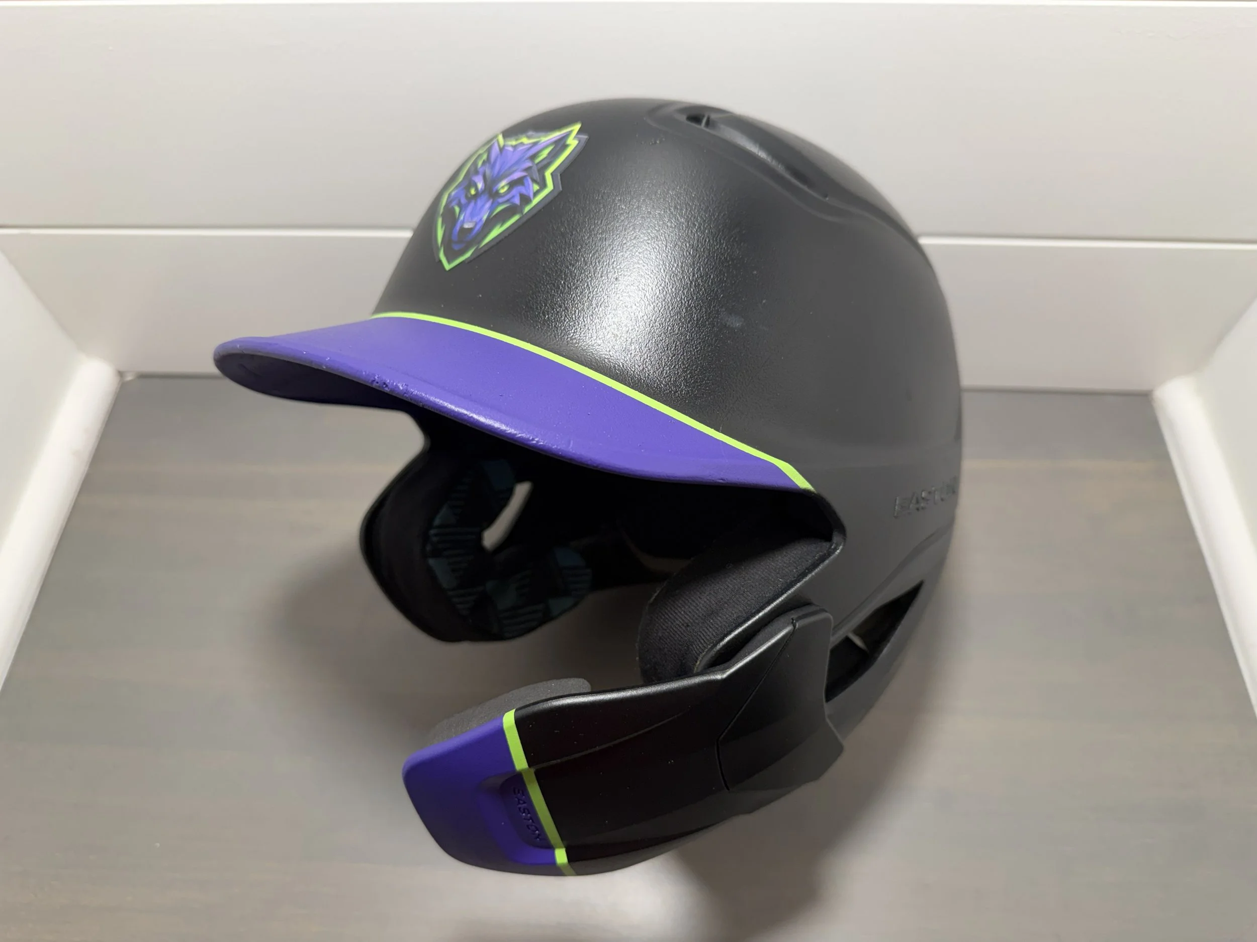 Black and purple bike helmet with neon green accents and a wolf logo on the front.