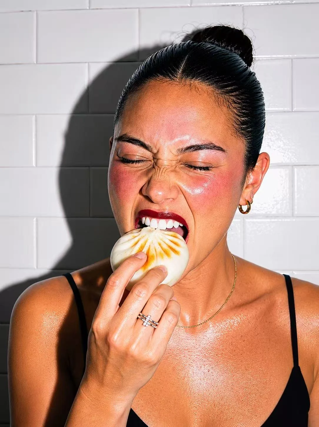 Woman taking a bite of a freshly steamed Chinese bao bun from Red Bao, featuring soft fluffy dough and savory filling, authentic Asian street food in Columbus, Ohio.