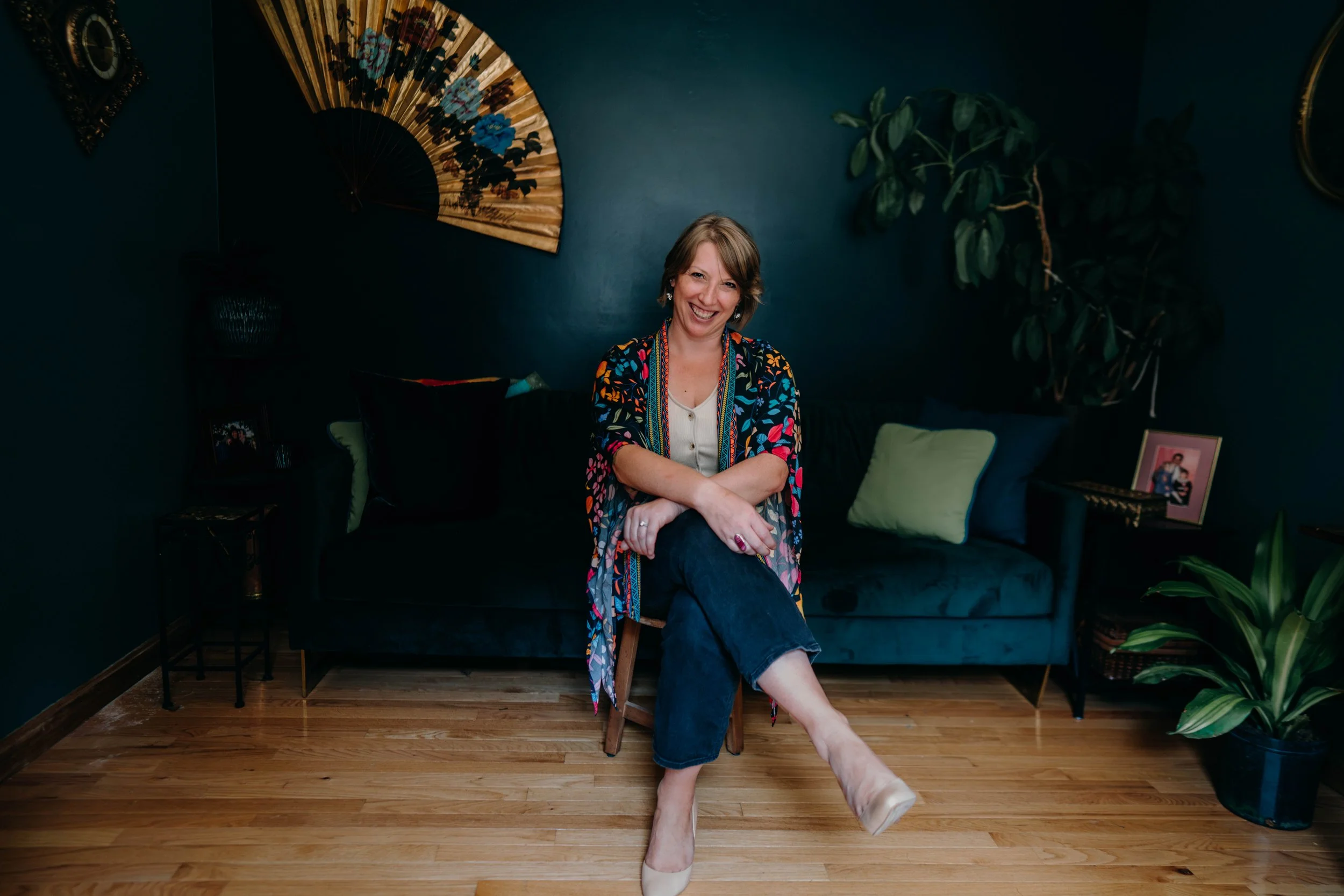 Beth sitting on a stool in her office smiling directly at the camera.
