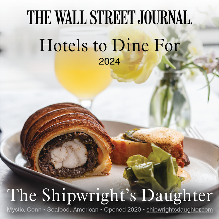 Cover of The Wall Street Journal magazine featuring a plate with a beef Wellington, green beans, and a side dish, with a glass of yellow beverage and white flowers in the background.