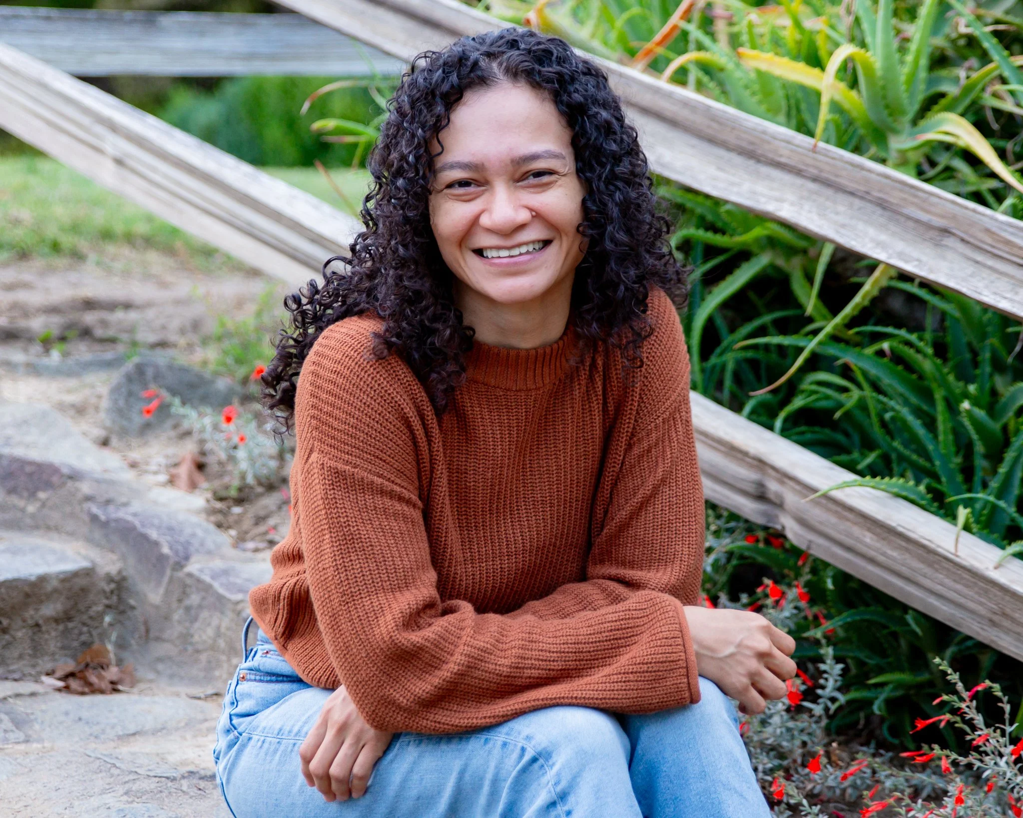 woman sitting on stairs smiling at camera. she is a trauma therapist sacramento