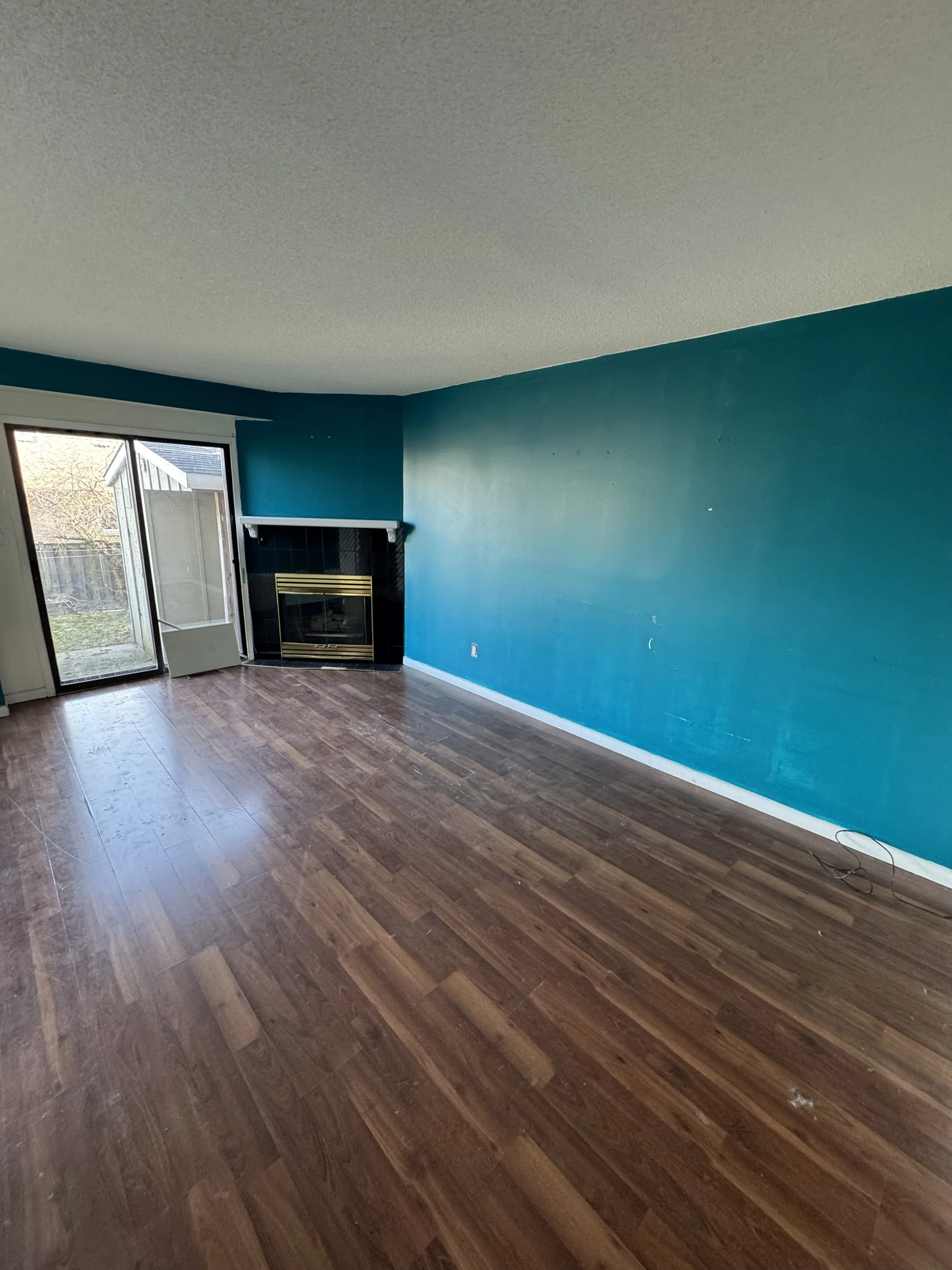 Living room before renovation featuring the original flooring and fireplace.