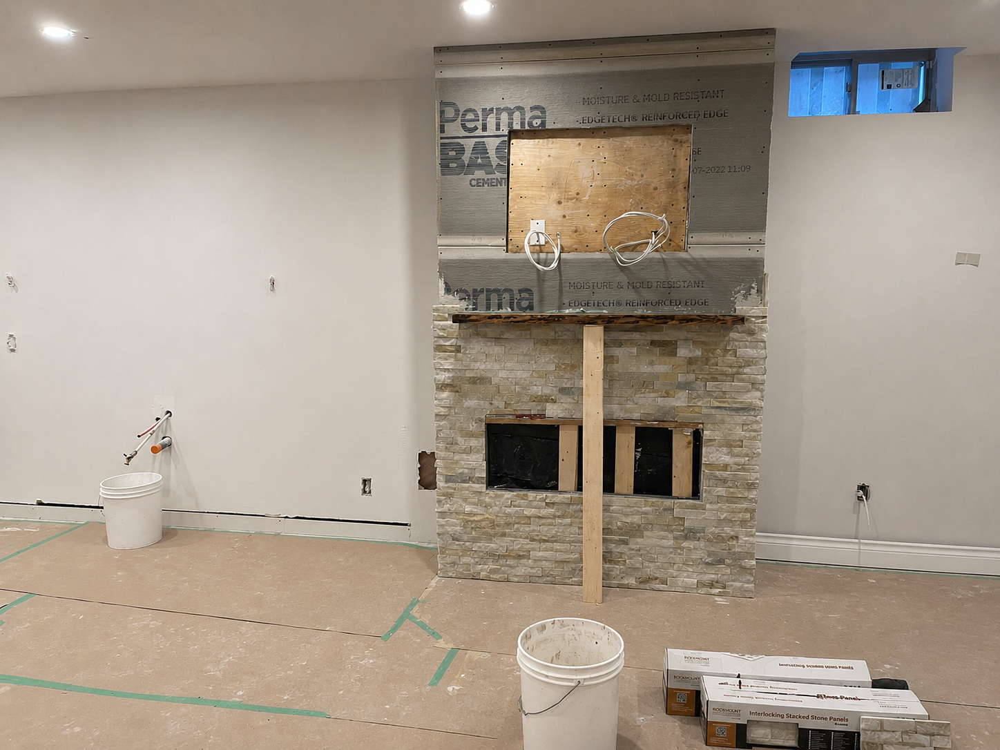 Basement feature wall with a stone fireplace under construction.