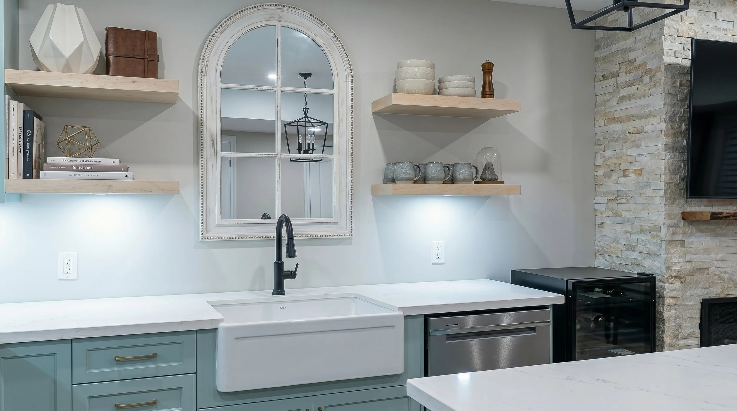Farmhouse sink with custom cabinetry, floating shelves and decorative feature wall.