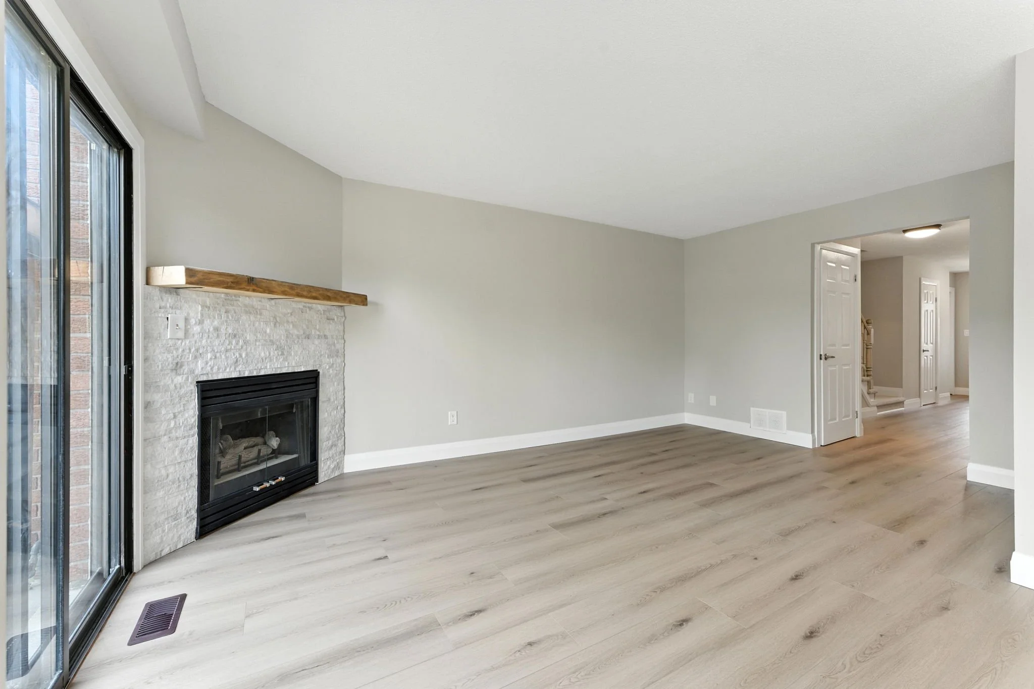 Bright open living room featuring modern fireplace, vinyl flooring and custom carpentry.