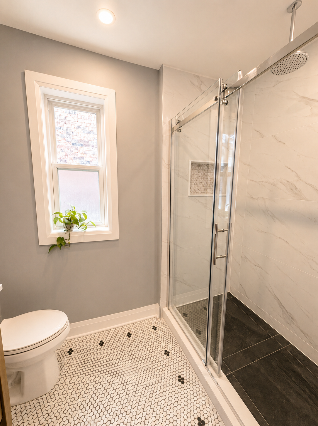 Finished walk-in shower with frameless glass enclosure, niche and modern fixtures.
