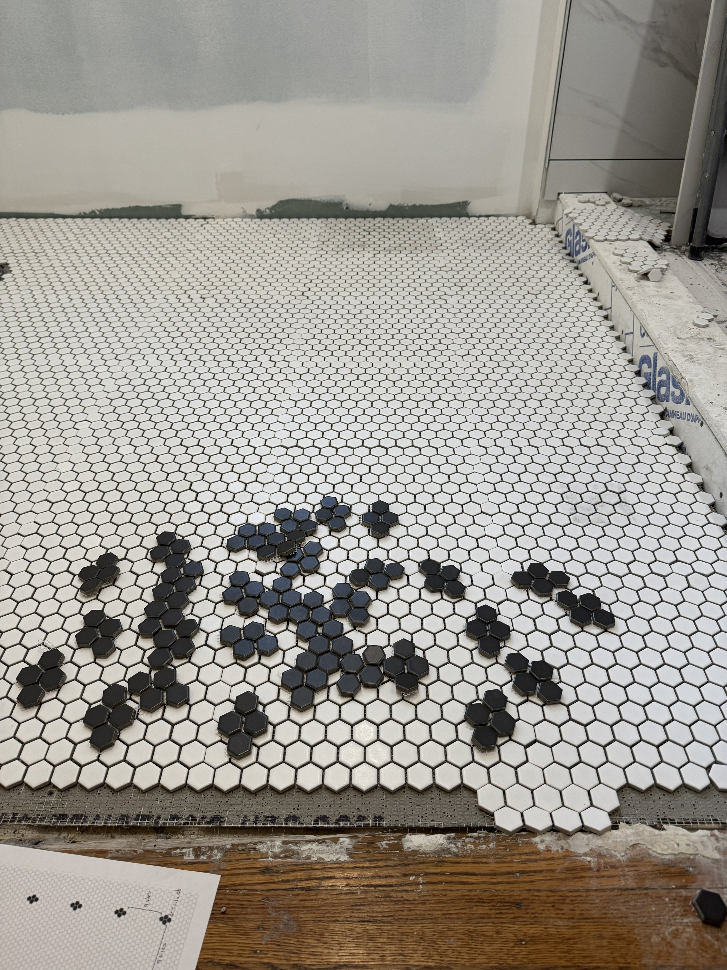 Close-up of penny tile layout planning on bathroom floor before installation.