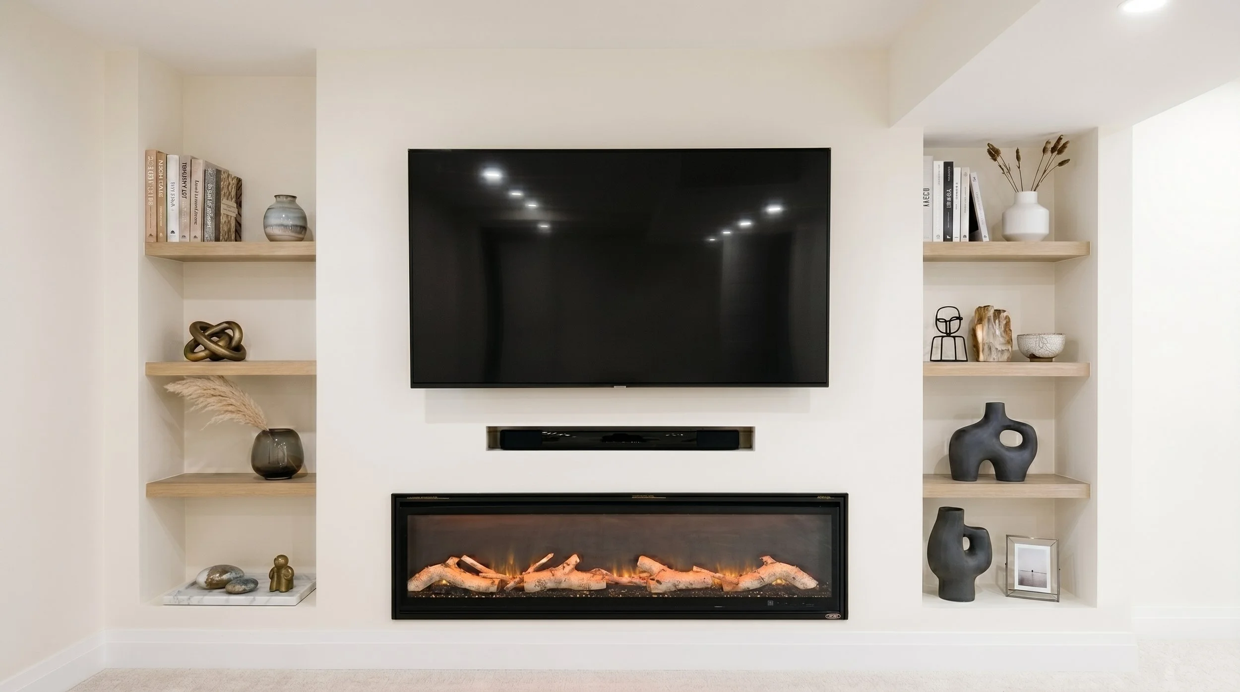 Custom media wall with built-in electric fireplace, floating shelves and integrated television.