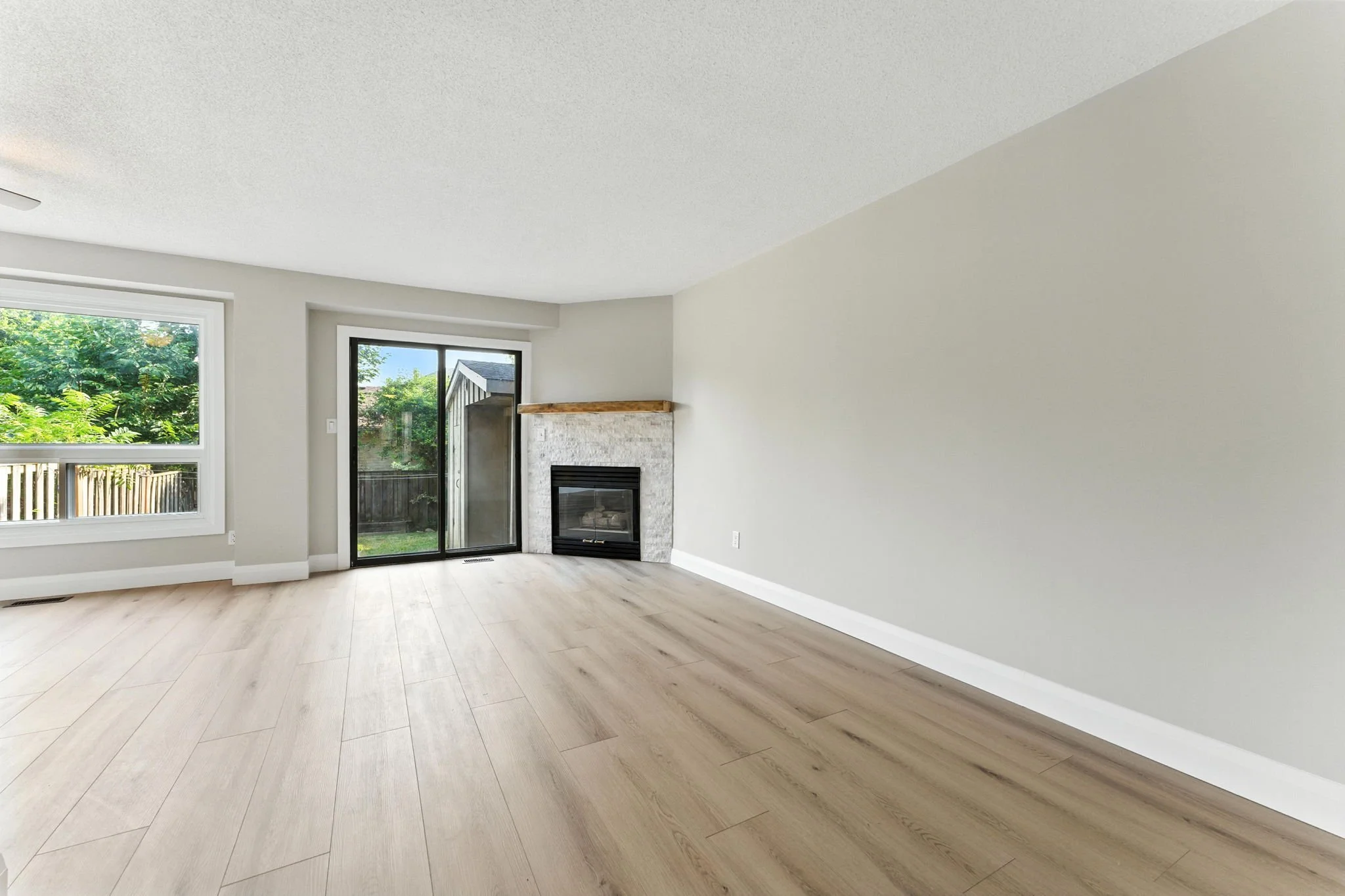 Bright open-concept living room with new flooring and a modernized fireplace.