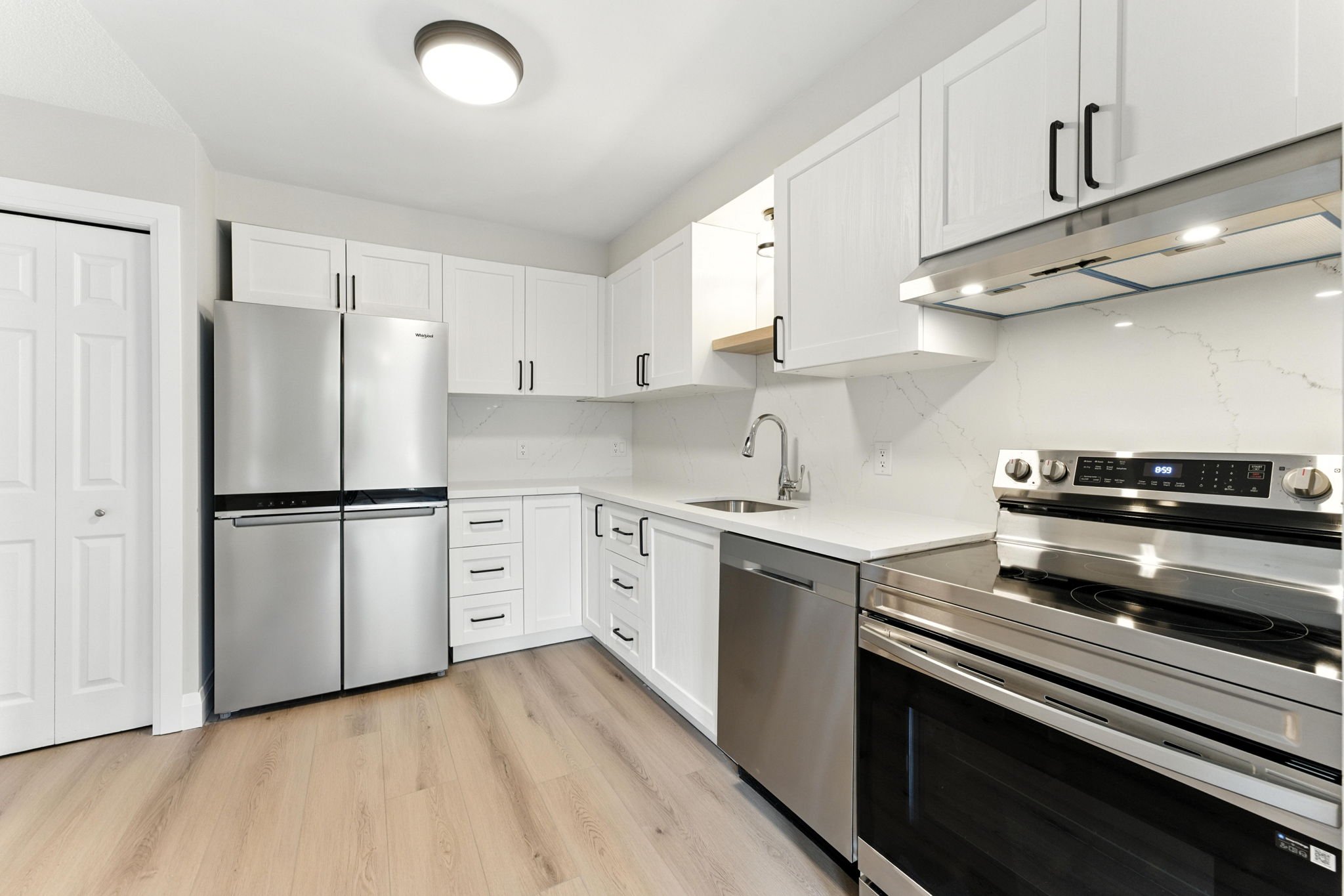 Renovated kitchen featuring custom cabinetry, stainless steel appliances and durable quartz countertop and backsplash.