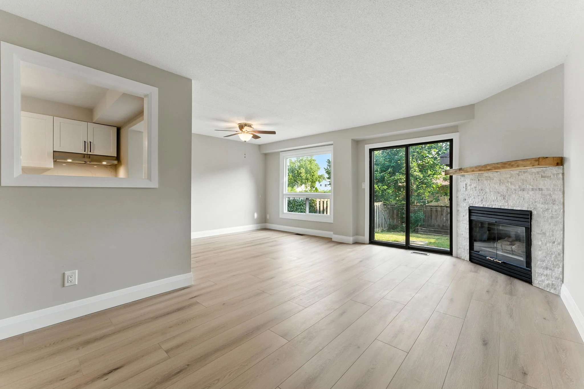 Bright open-concept living room created through a complete home renovation with a new fireplace, new flooring, natural light and seamless indoor-outdoor flow.