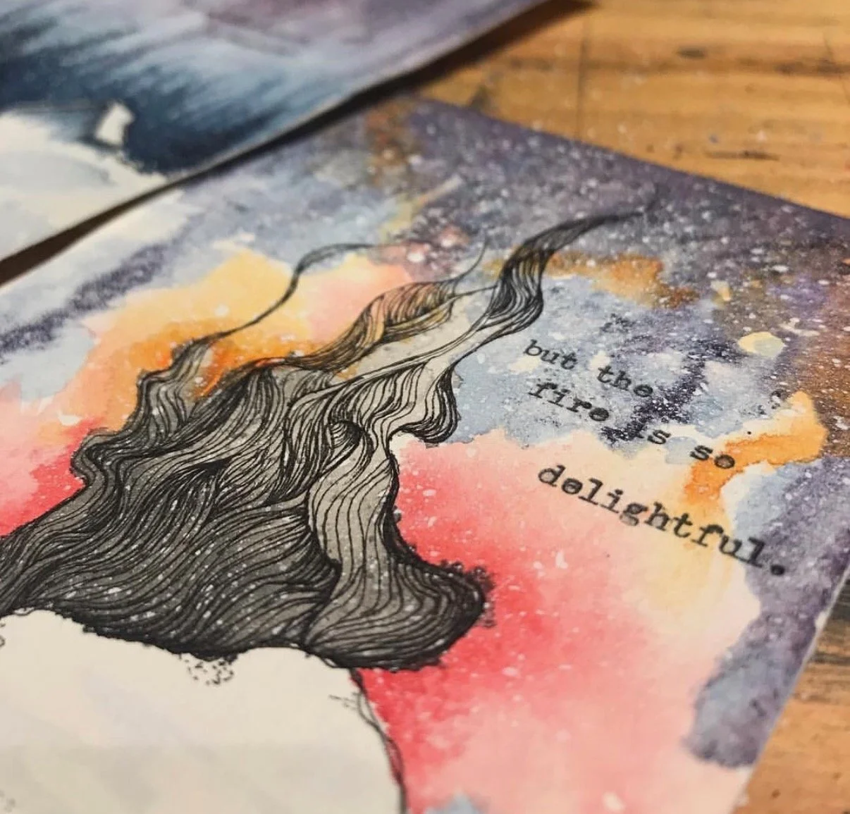 Close-up of watercolor artwork featuring a fire burning on a snowy hill against a starry night sky. The quote, "but the fire is so delightful" is typed on it.