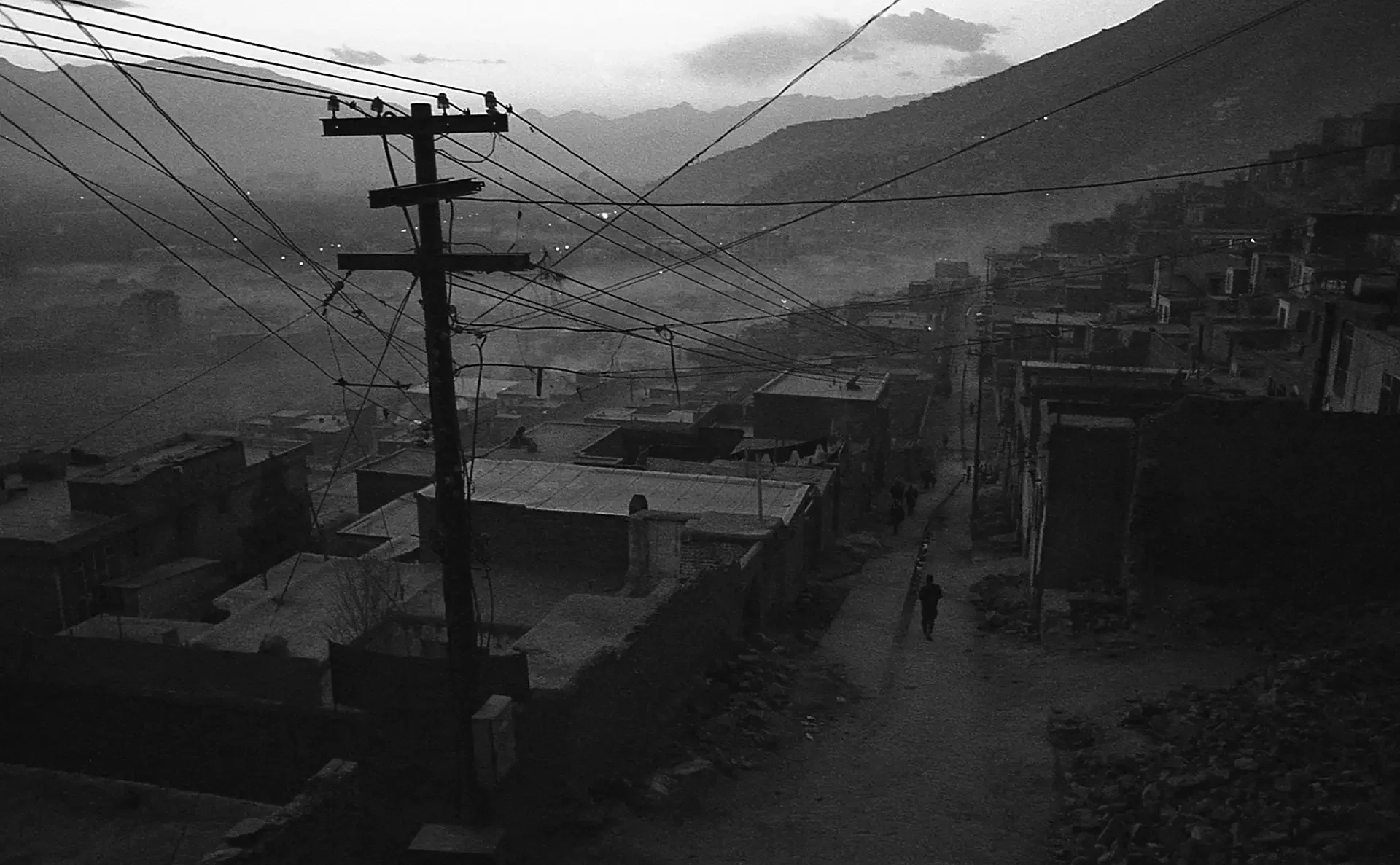 Low-key landscape photography capturing a hillside Kabul and utility poles at dusk, Afghanistan.