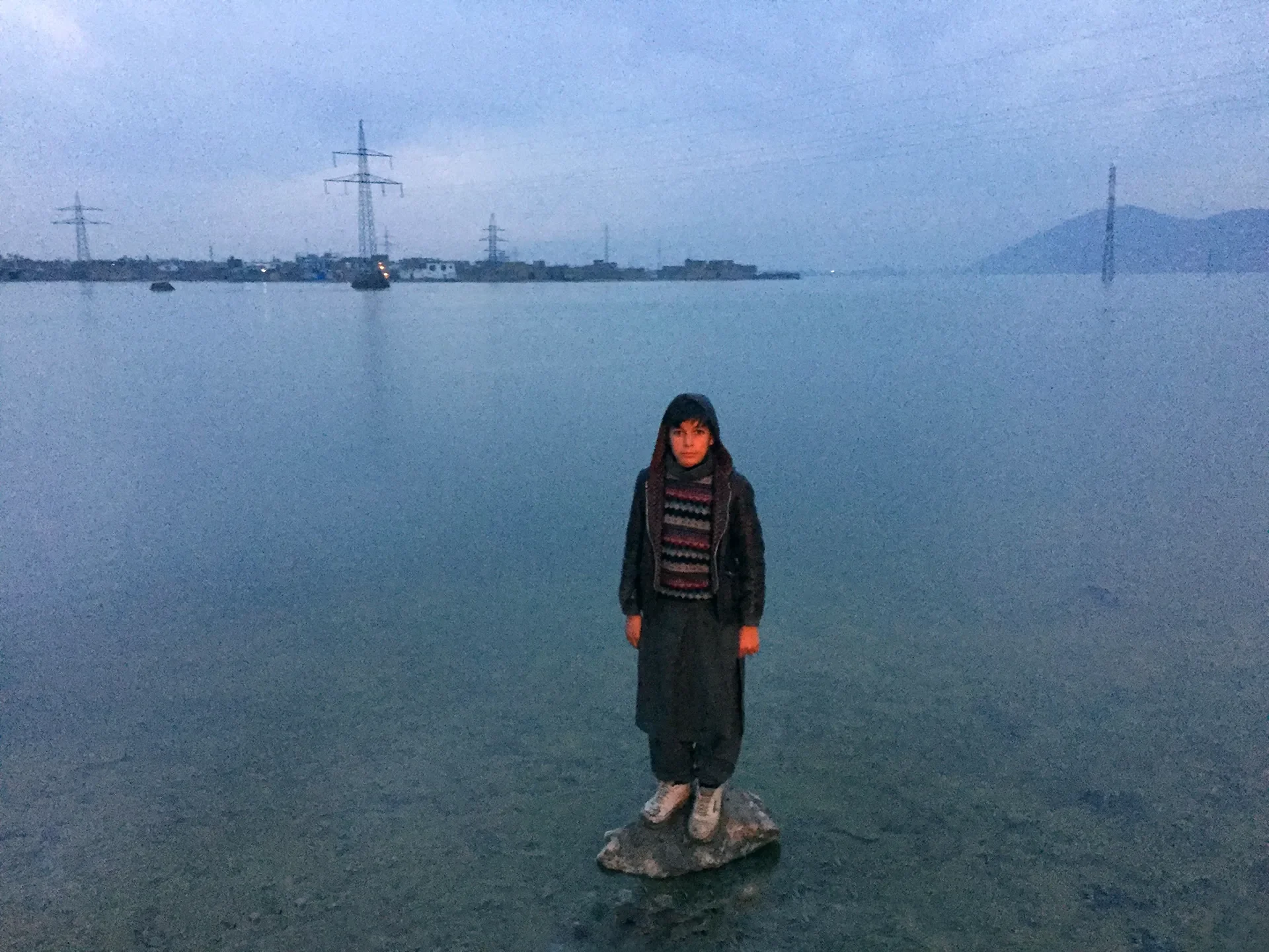 Documentary photography of a person standing by a vast body of water, Kabul, Afghanistan.
