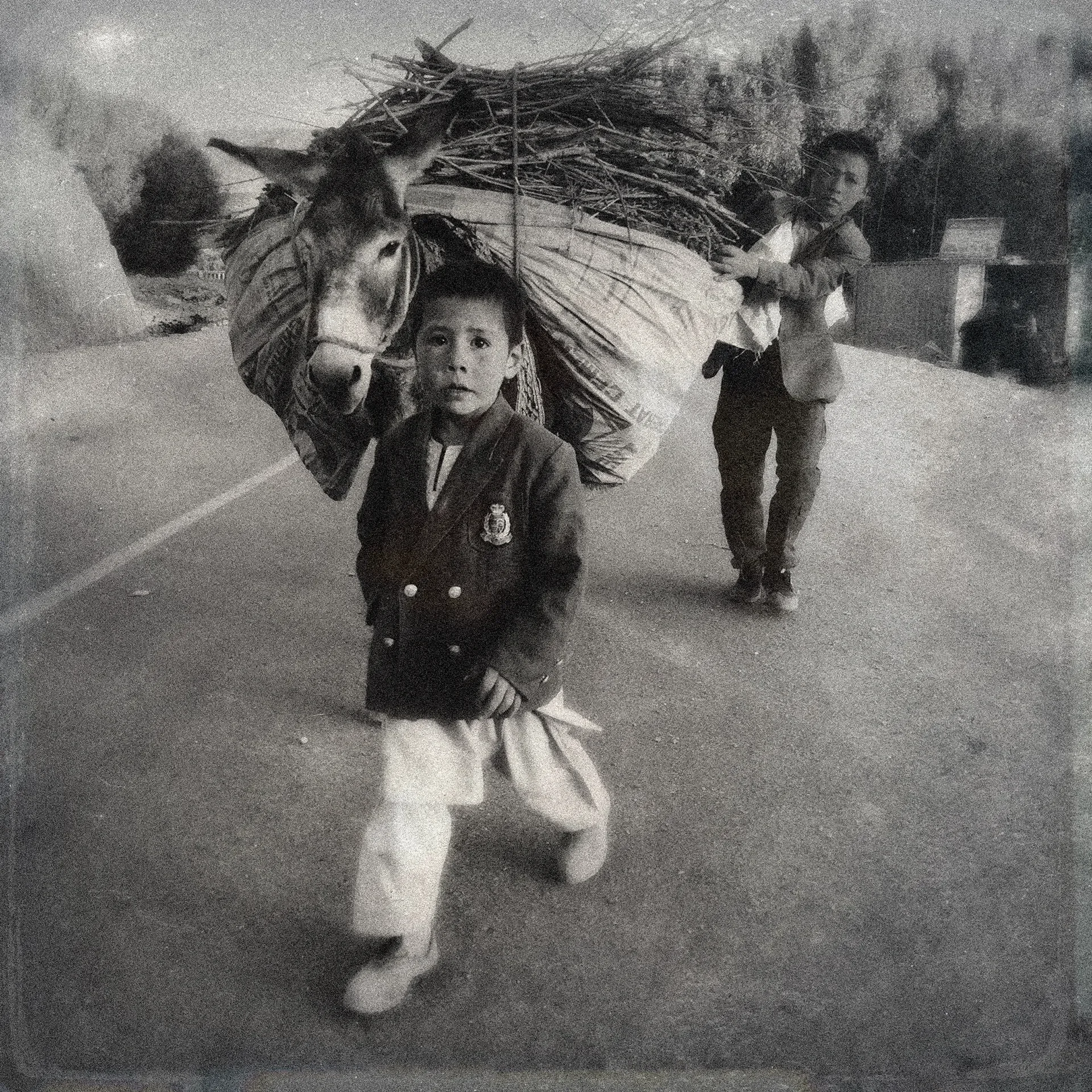 Documentary photography capturing a child carrying a heavy bundle on a street, Bamian, Afghanistan.⁠