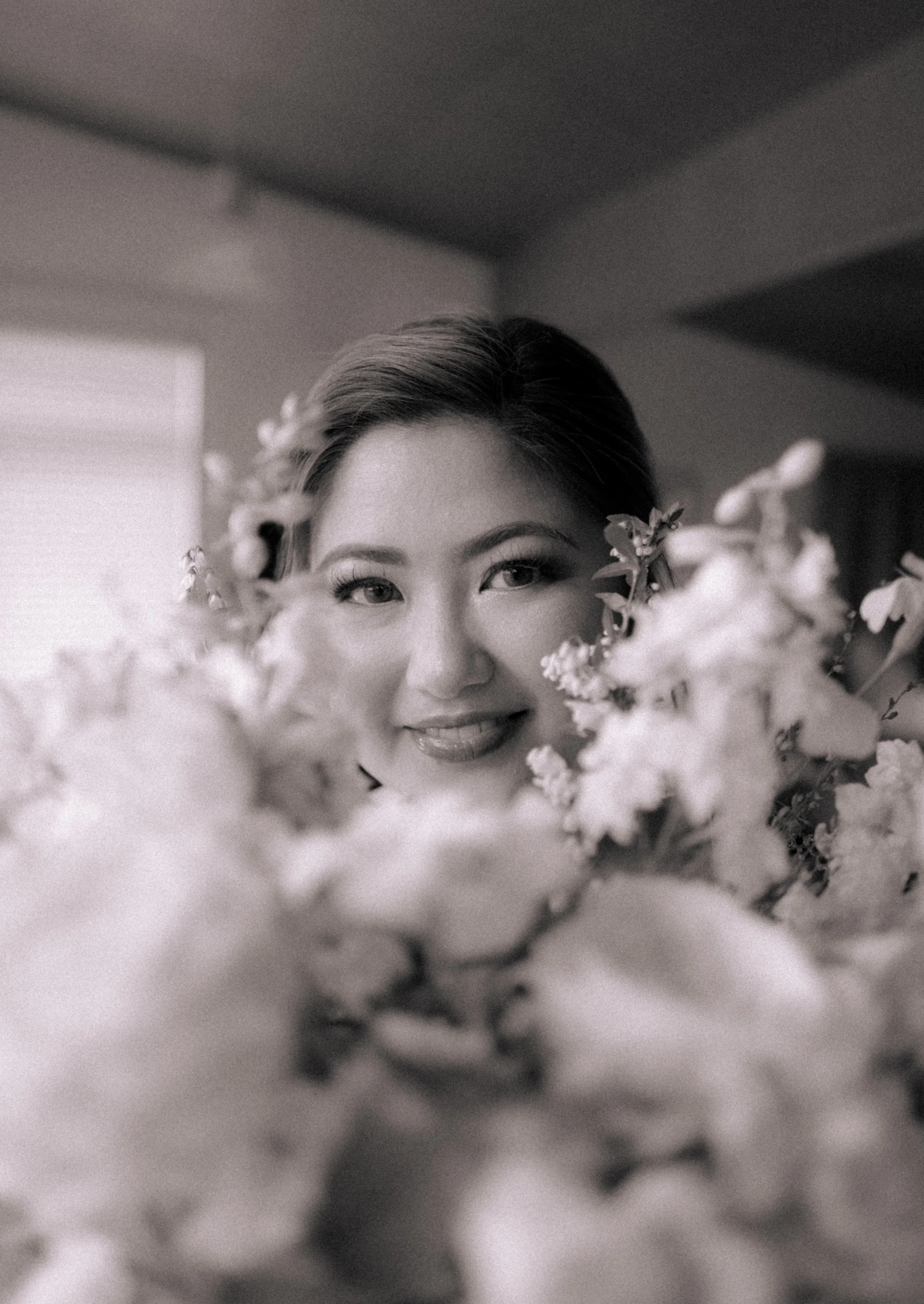 A woman smiling behind a bouquet of flowers.