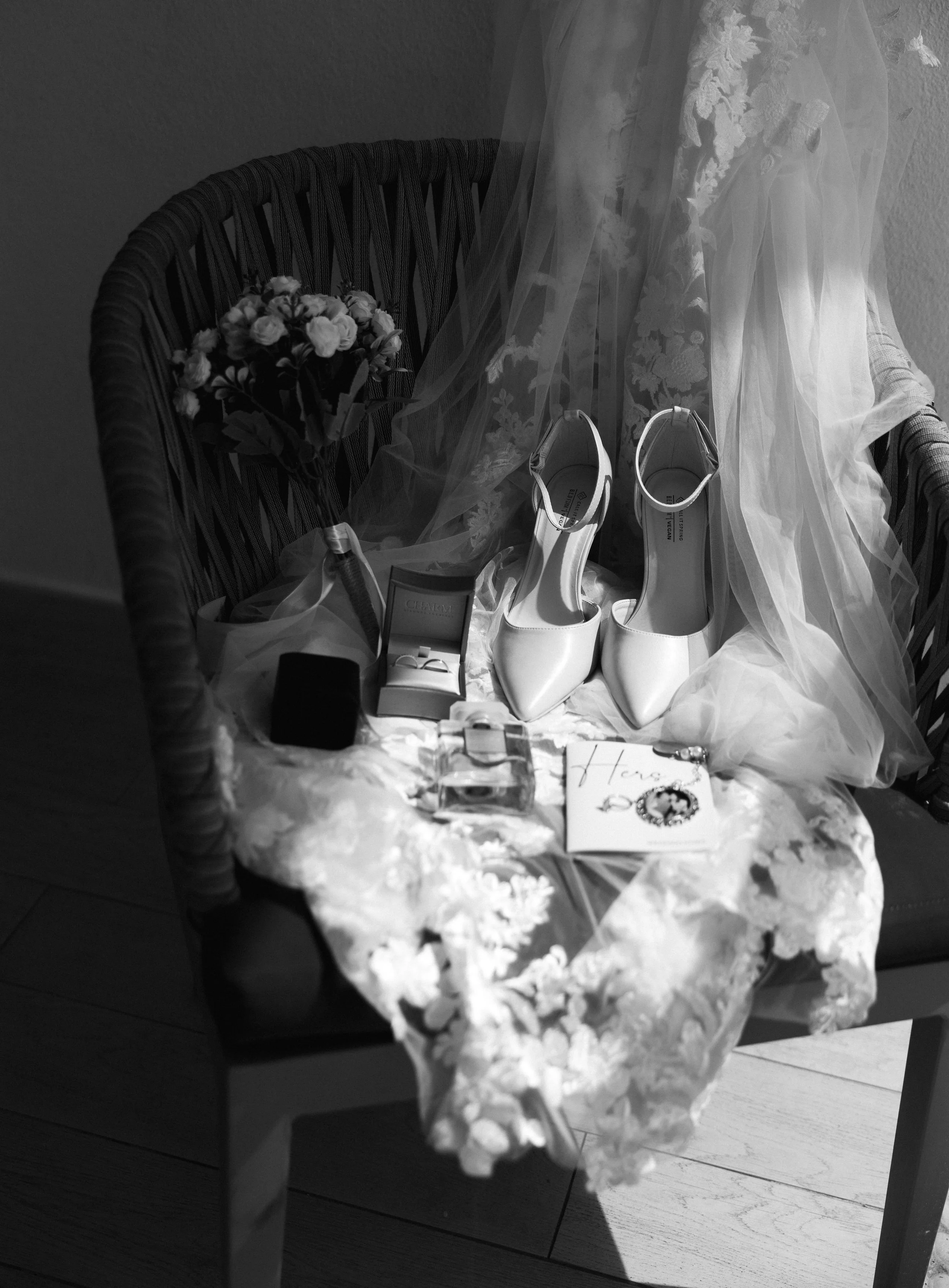 Wedding shoes, a veil, jewelry, a bouquet, and a 'Happily Ever After' card displayed on a chair.
