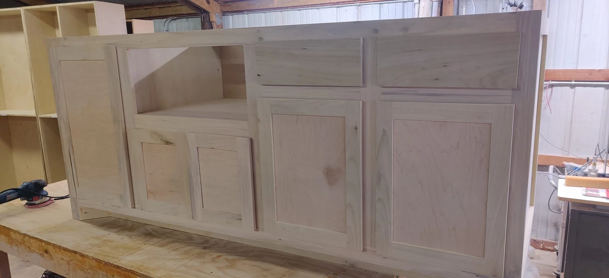 Unfinished wooden cabinet or furniture piece in a woodworking shop.