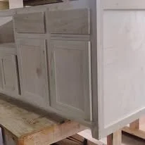 Close-up of painted cabinet drawers and door fronts in a light gray color on a wooden surface.