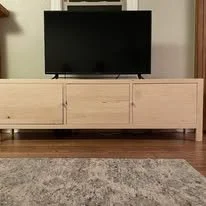 Flat-screen TV on a wooden media console in a living room.