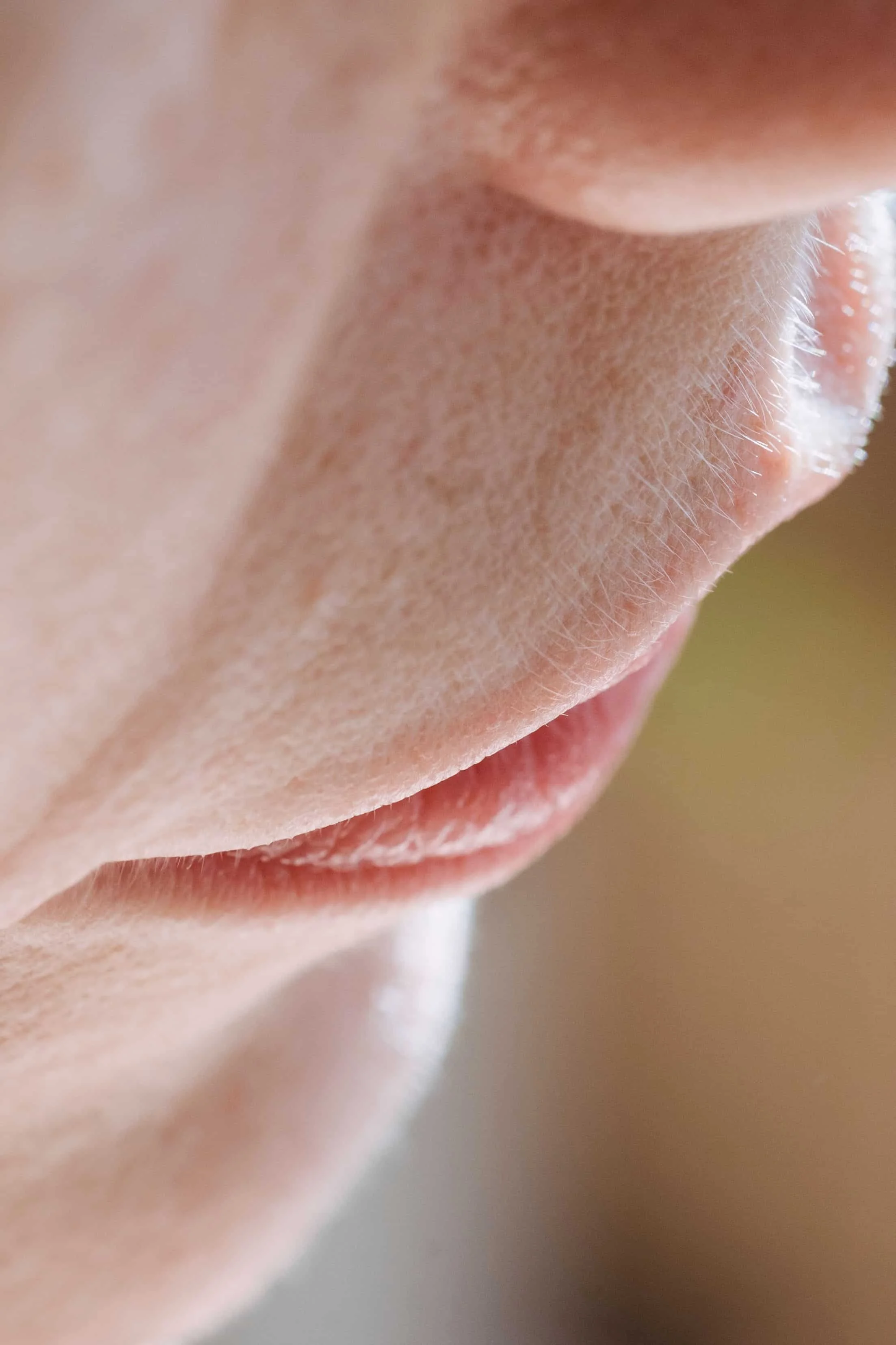 Close-up of a person's nose and part of the mouth, with visible skin texture and fine facial hair.