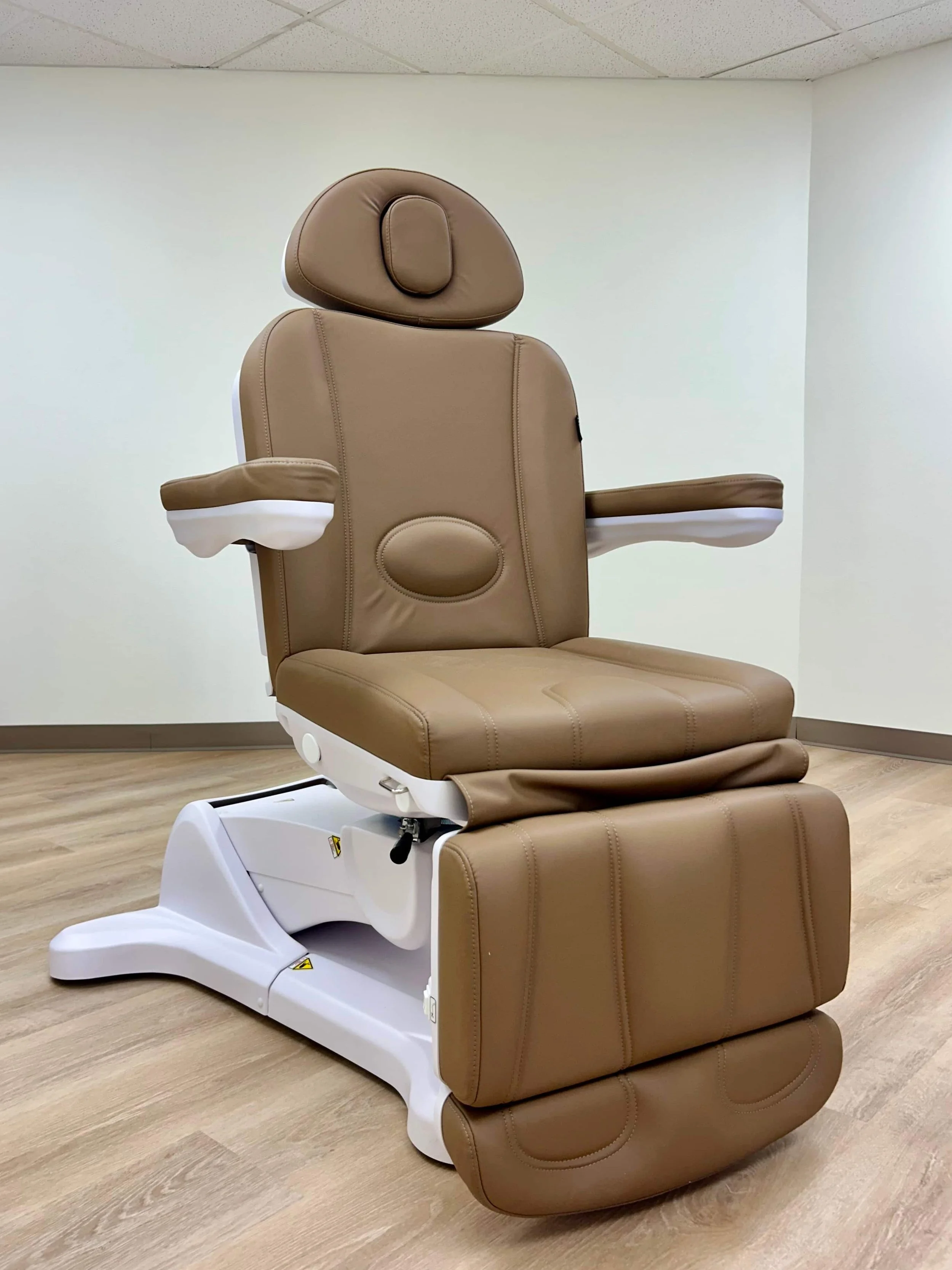 Medical examination chair with beige upholstery in a clinic or hospital room.