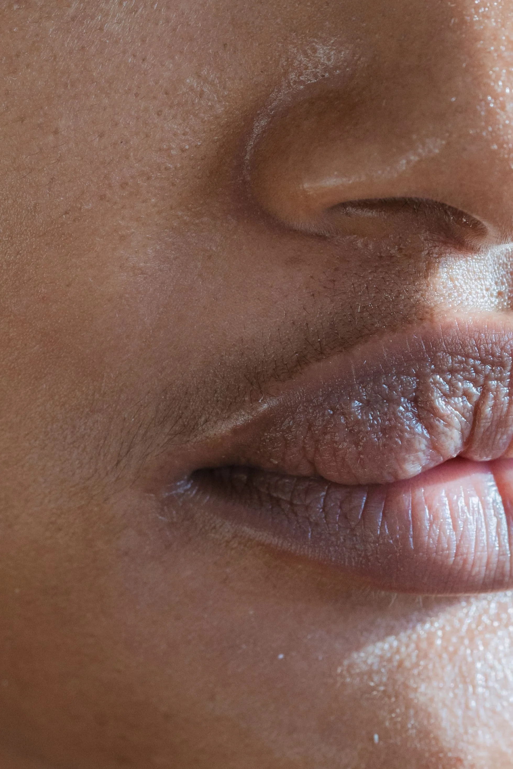 Close-up of person's nose, lips, and part of their cheek with detailed skin texture.