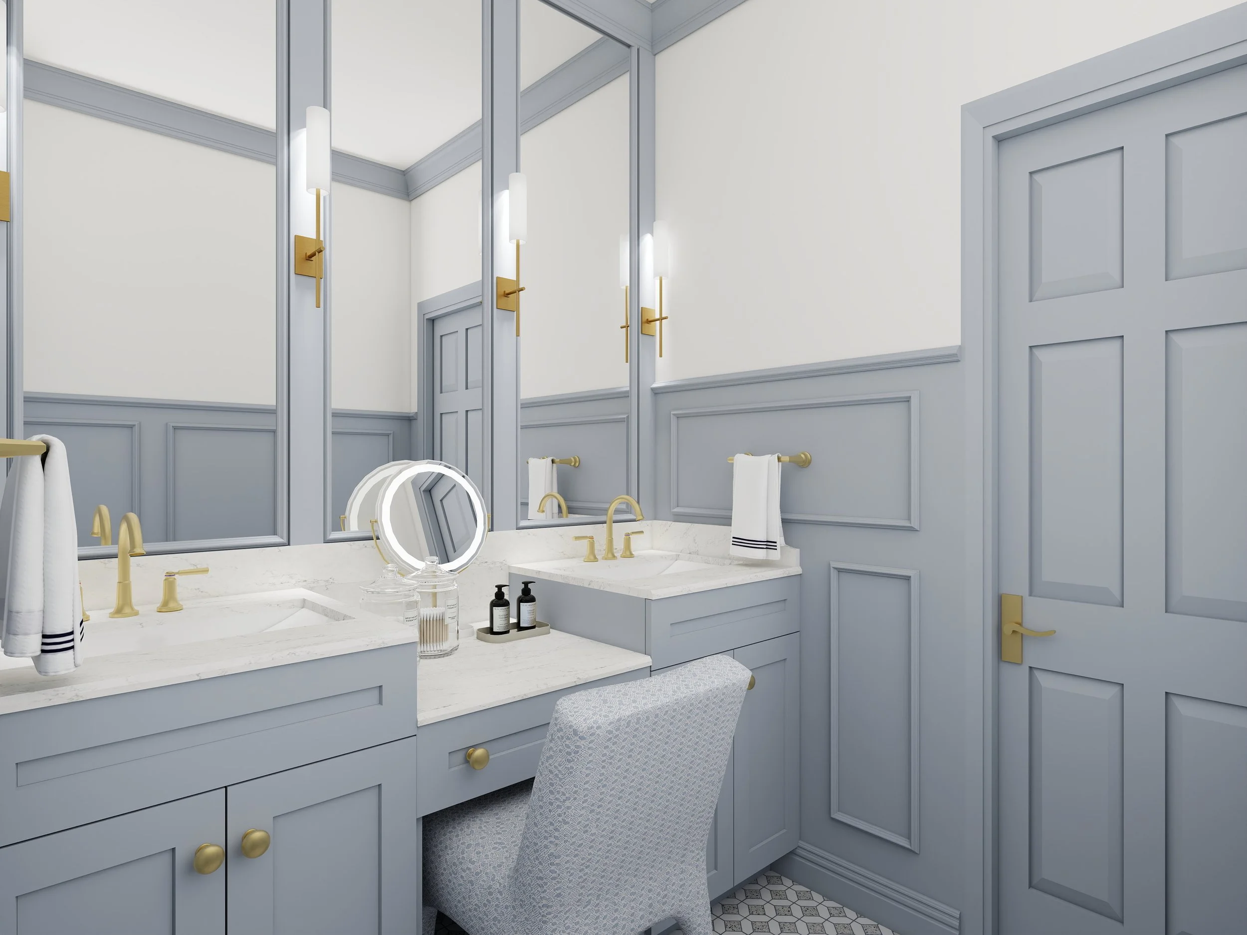 A luxurious bathroom with light blue cabinetry, gold hardware, and a marble countertop. The mirror and wall sconces are framed in gold, and there are various bottles and a small tray on the countertop. The wall has decorative paneling, and a cushione