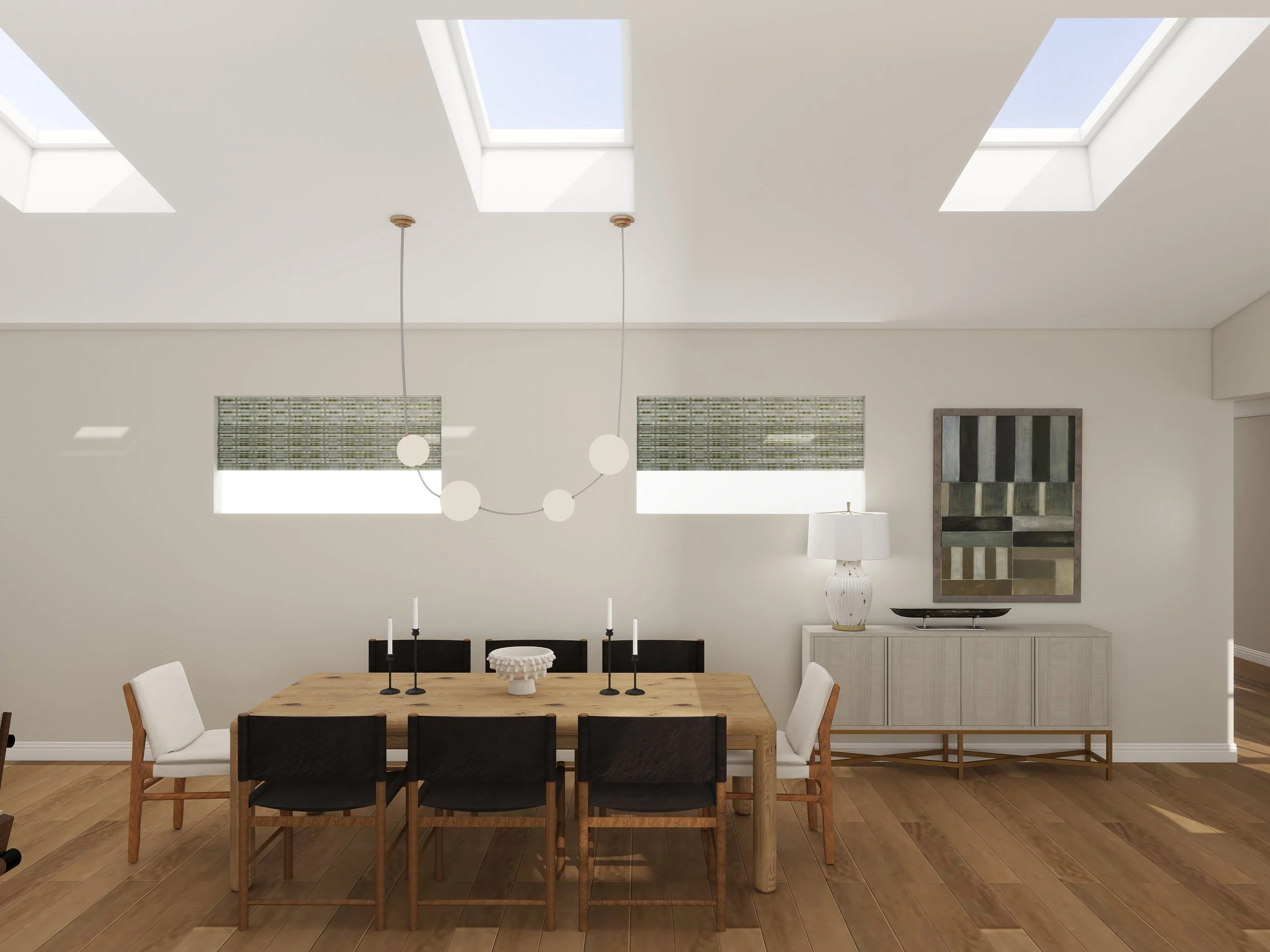 Modern dining room with a wooden table, white and black chairs, three black candlesticks with white candles, a white decorative bowl, framed abstract artwork on the wall, white cabinet, lamp, and three skylights in a white ceiling.