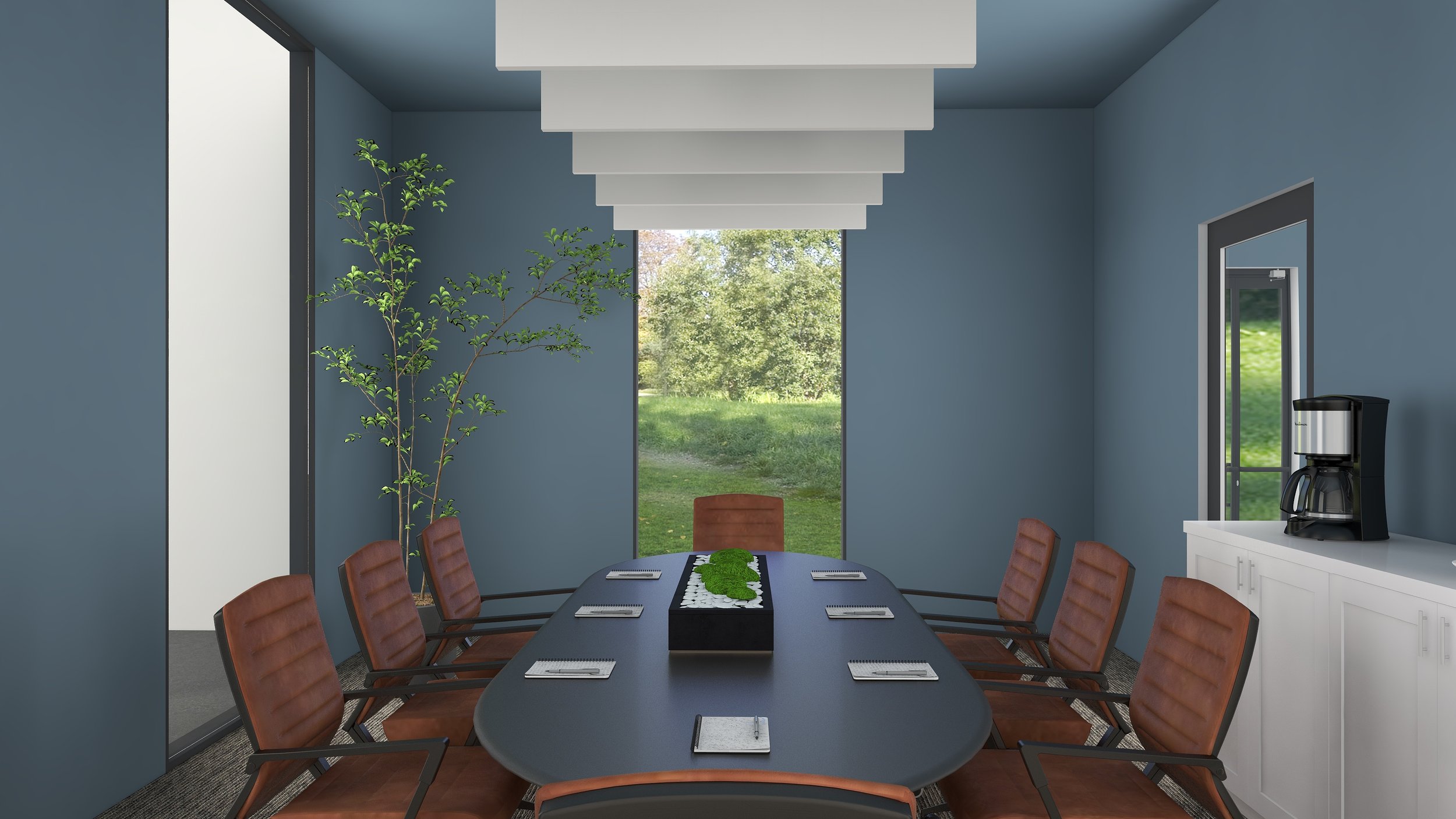 A conference room with a large oval table surrounded by brown chairs, a window showing a view of grass and trees, a potted plant in the corner, and a coffee maker on a white cabinet.