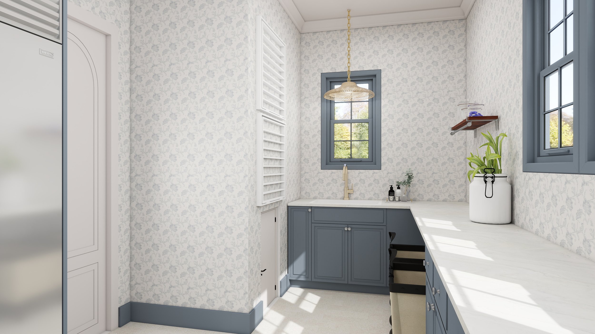 A small kitchen with white floral wallpaper, blue window frames, a white countertop, and a blue cabinet below the window. Decor includes a white vase with green plants and a wall shelf with small items. Natural light from the windows illuminates the 
