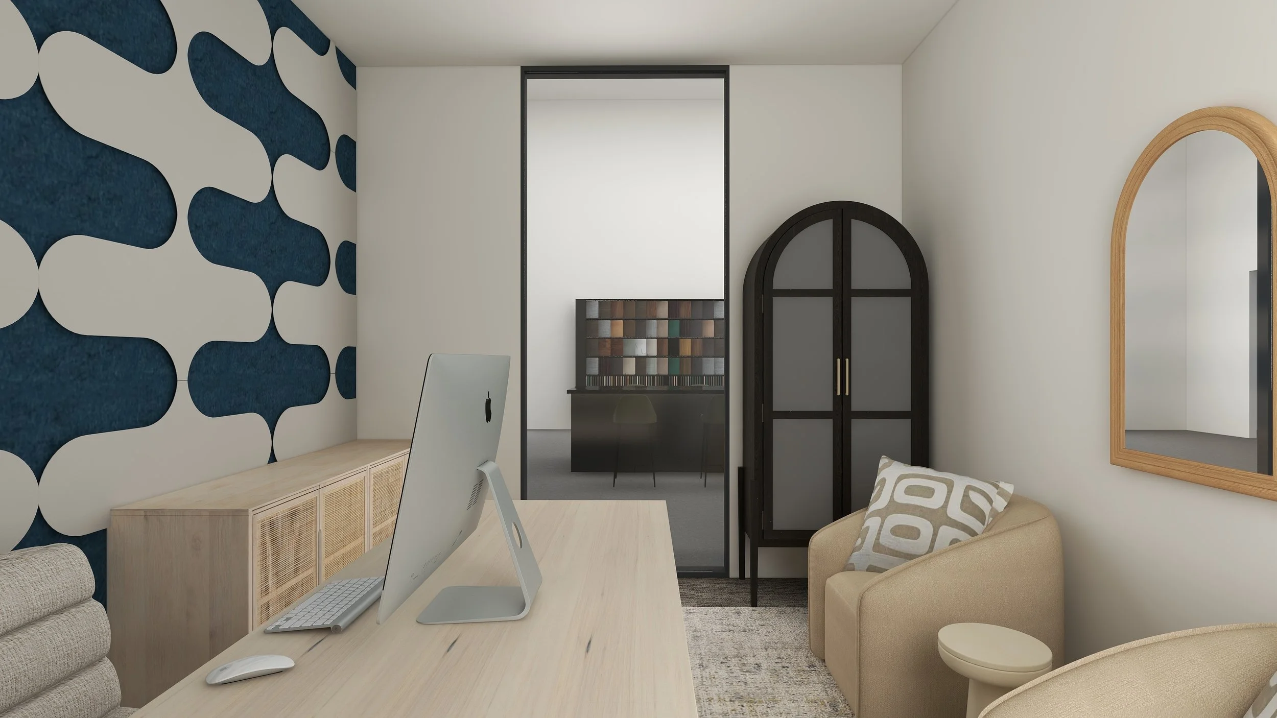 A modern workspace with a light wooden desk, an iMac computer, a beige sofa with patterned pillows, and decorative wall elements including a large mirror and a black arched doorframe.