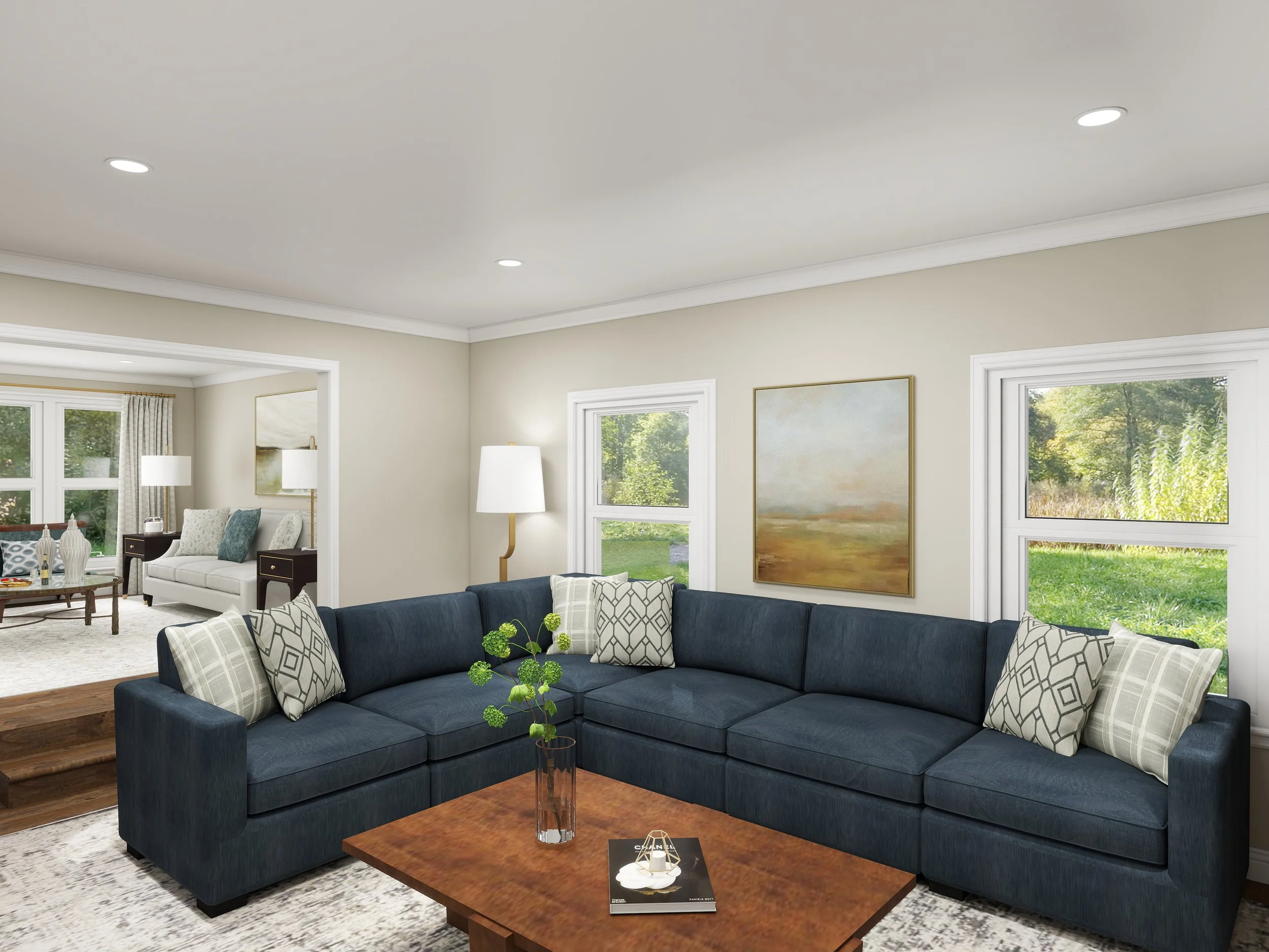 Living room with navy blue sectional sofa, patterned throw pillows, a wooden coffee table with a magazine and a small decorative item, and large windows showing greenery outside.