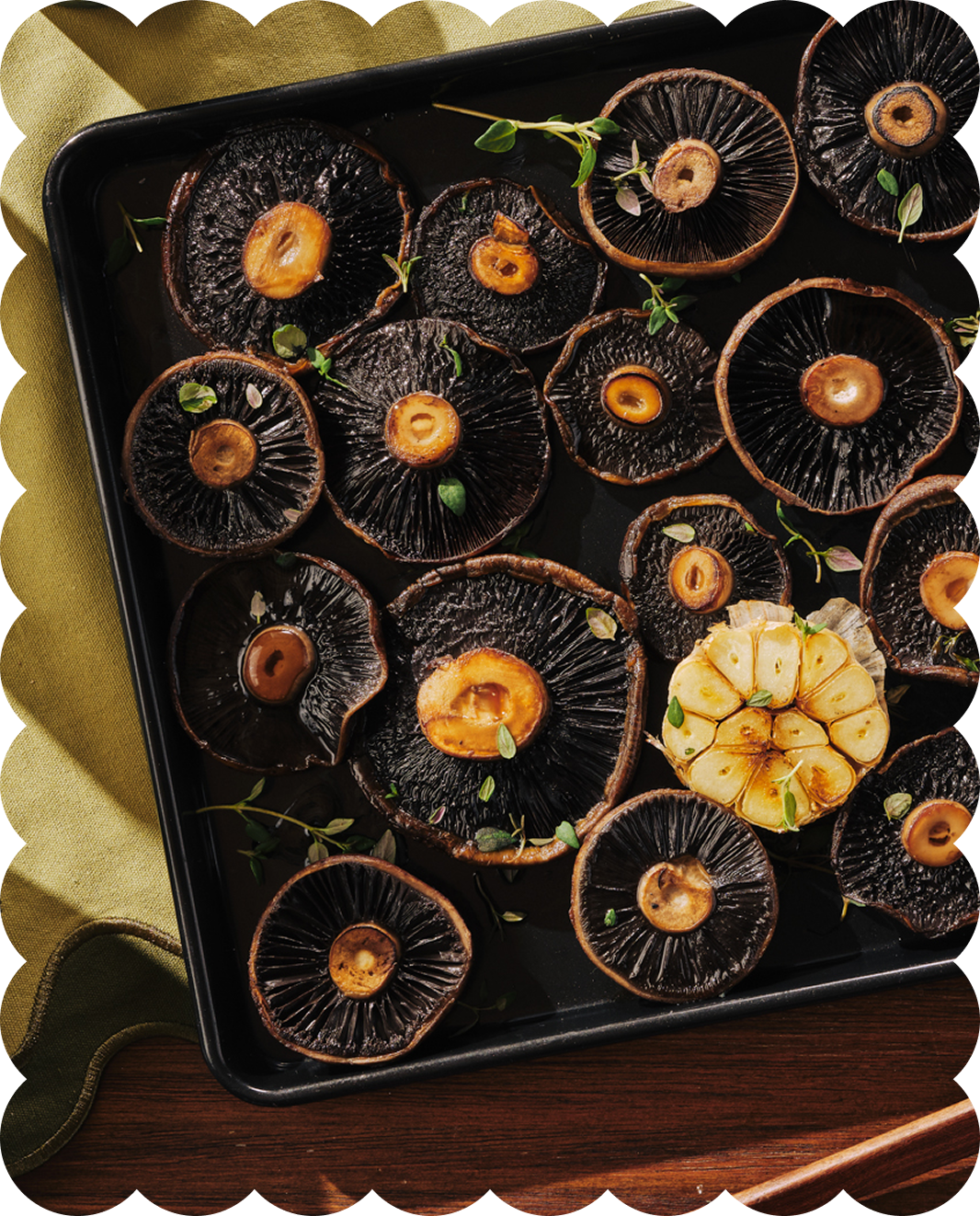 Roasted black mushrooms garnished with microgreens on a black baking tray.