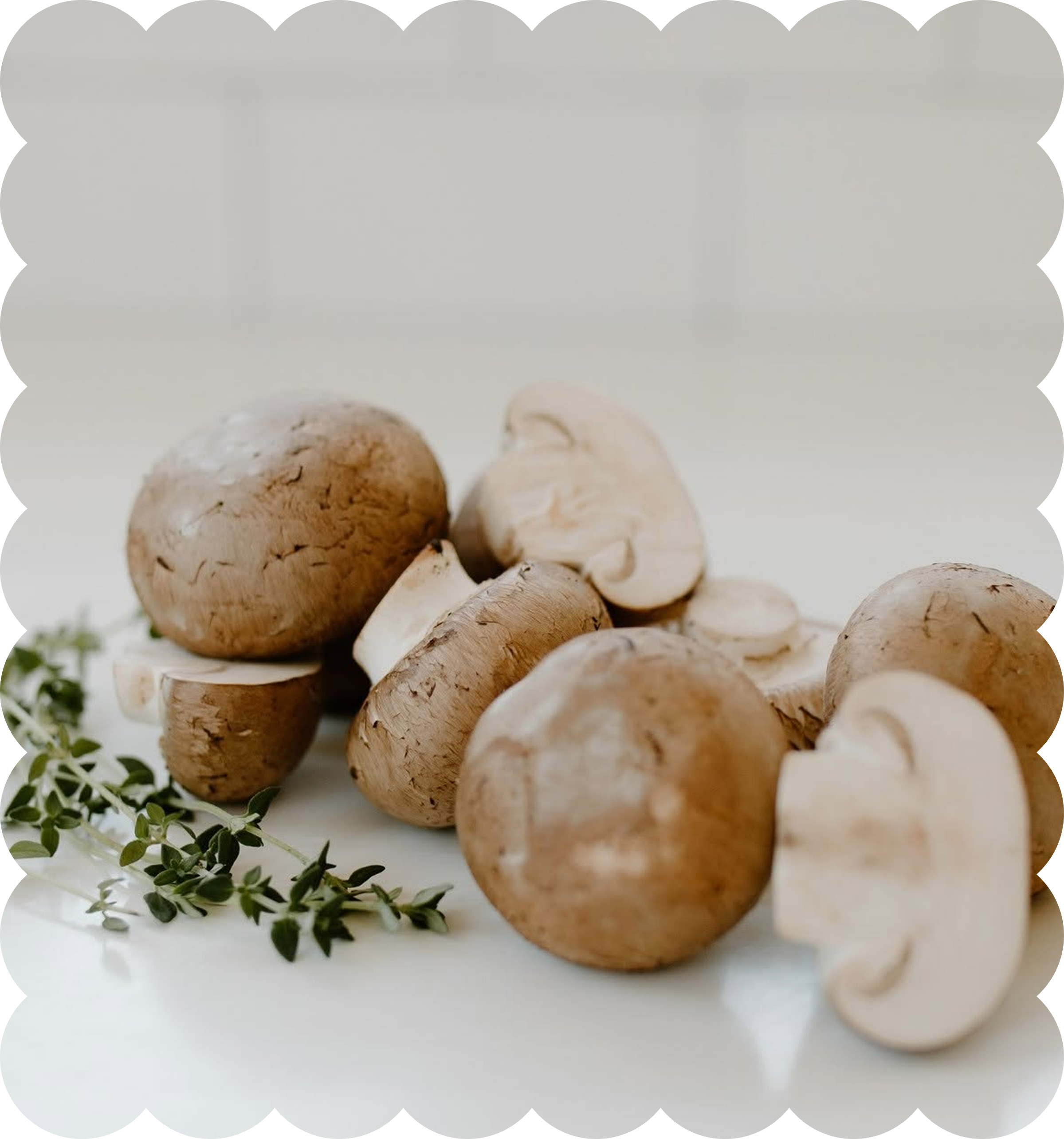 Close-up of sliced white button mushrooms with sprigs of fresh green thyme on a white surface.
