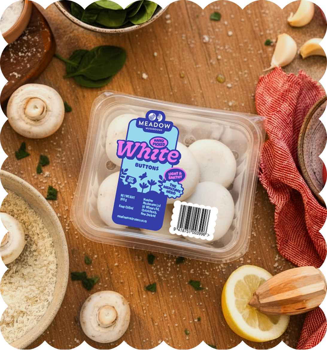 A container of Meadow Mushrooms White Buttons on a wooden table surrounded by fresh mushrooms, lemon, garlic, and herbs.