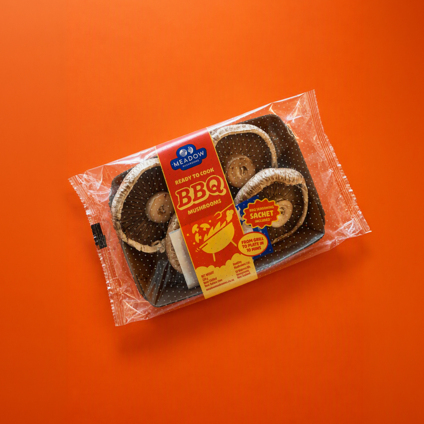 Package of Meadow Mushrooms BBQ flavor ready to cook, in clear plastic with red and yellow label, on orange background