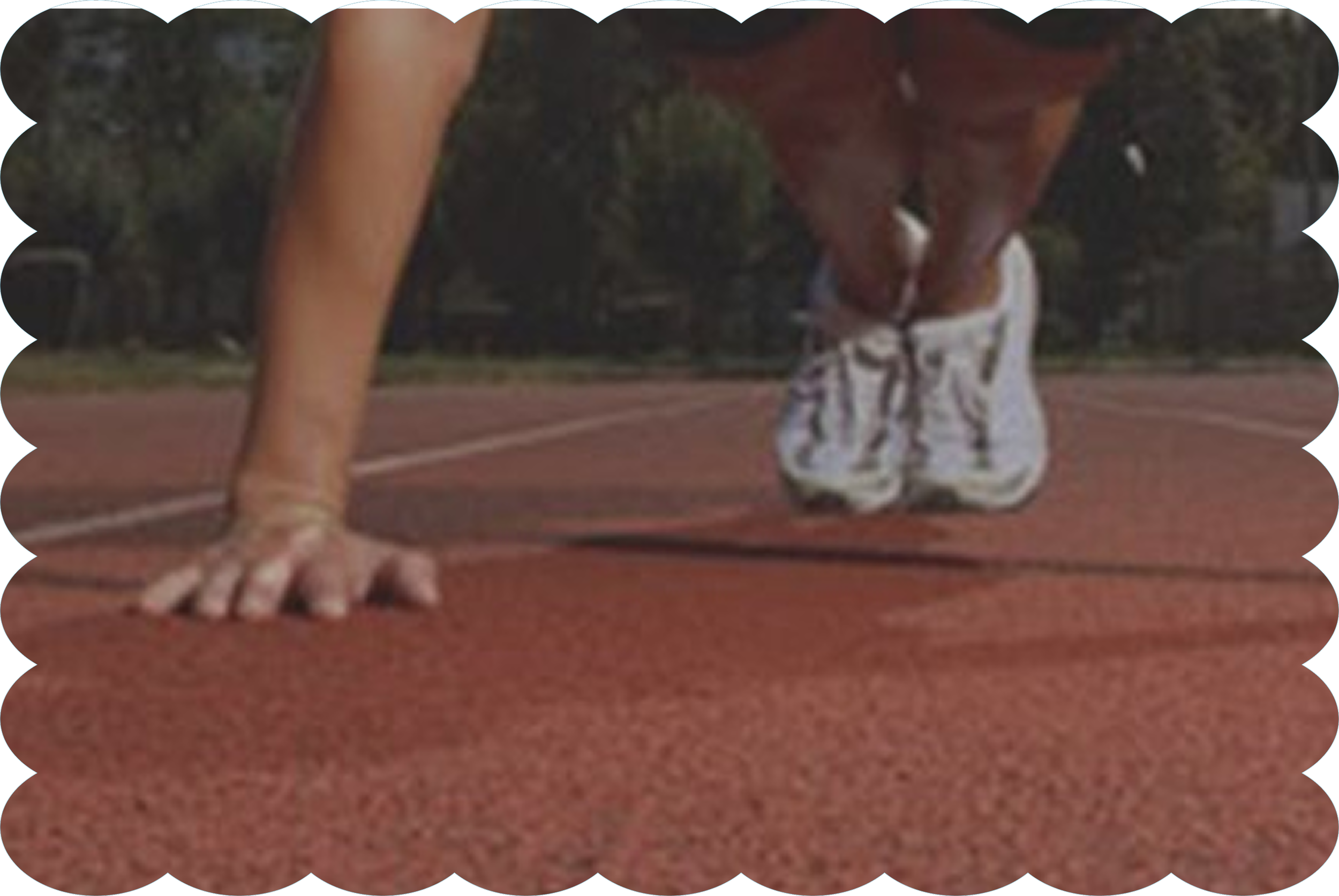 A person on a running track in a starting position, with only their legs and feet visible, wearing shorts and barefoot. Another person's legs and feet are visible in the background, wearing athletic shoes.