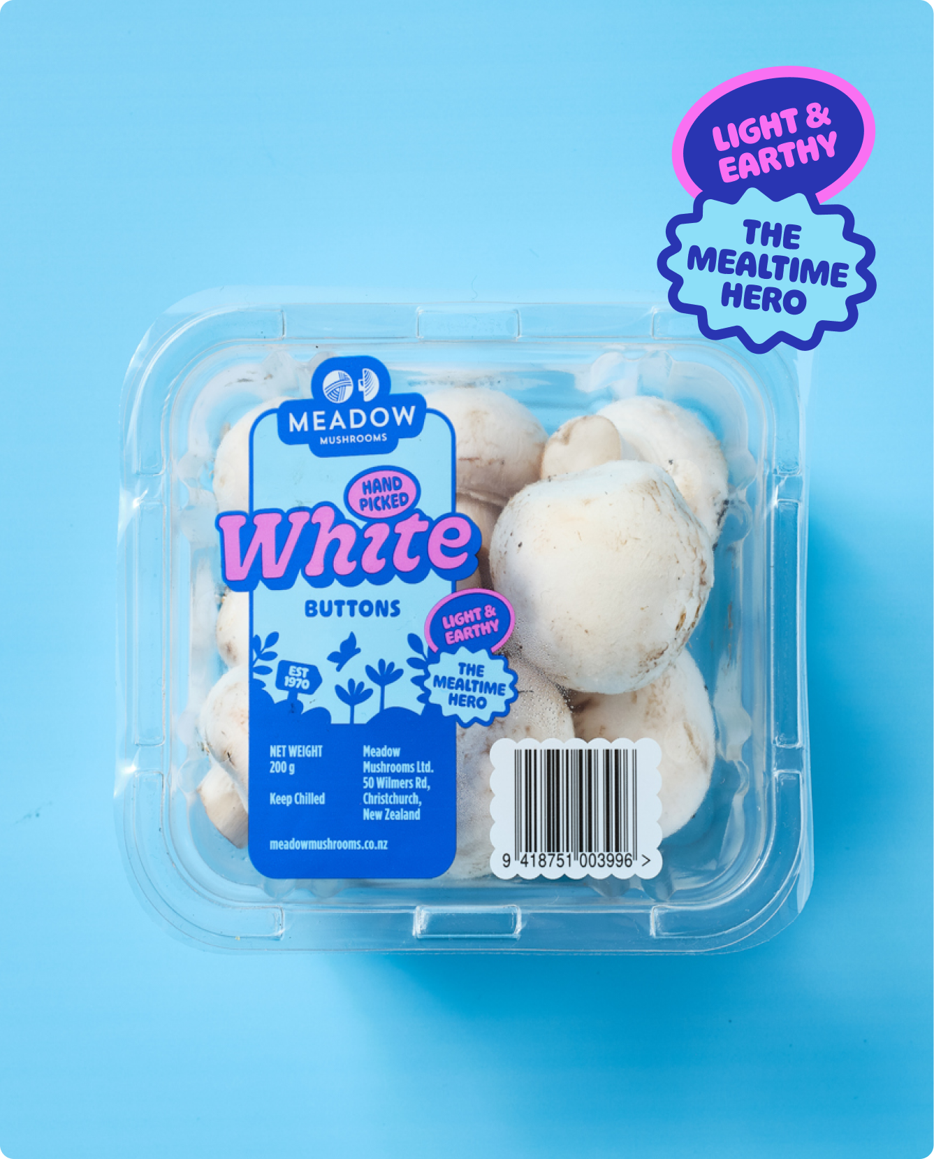 A clear plastic container of fresh white mushrooms on a blue background with colorful labels and stickers.