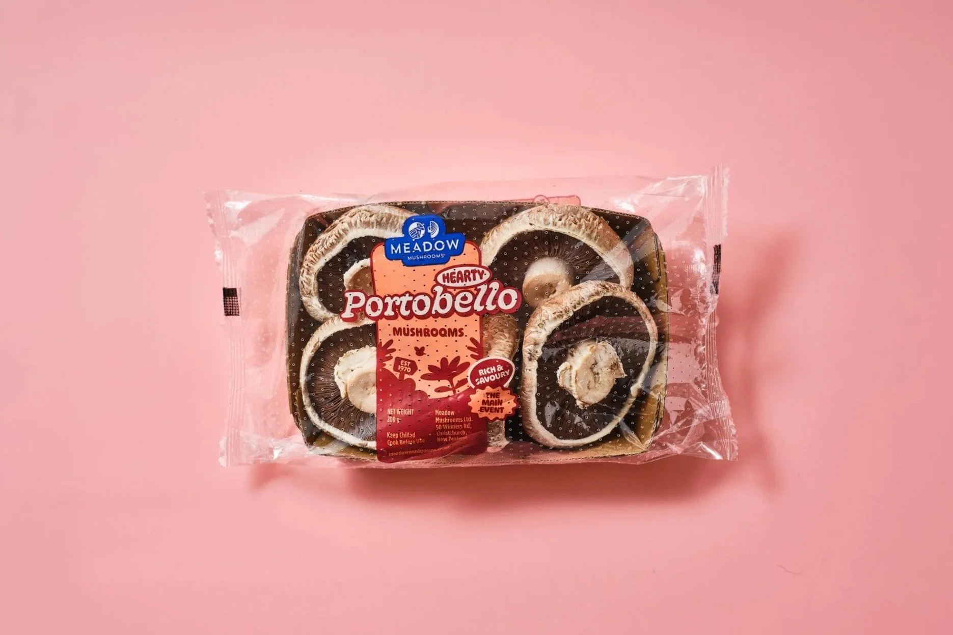 Packaged Meadow Mushroom Portobello mushrooms on pink background.