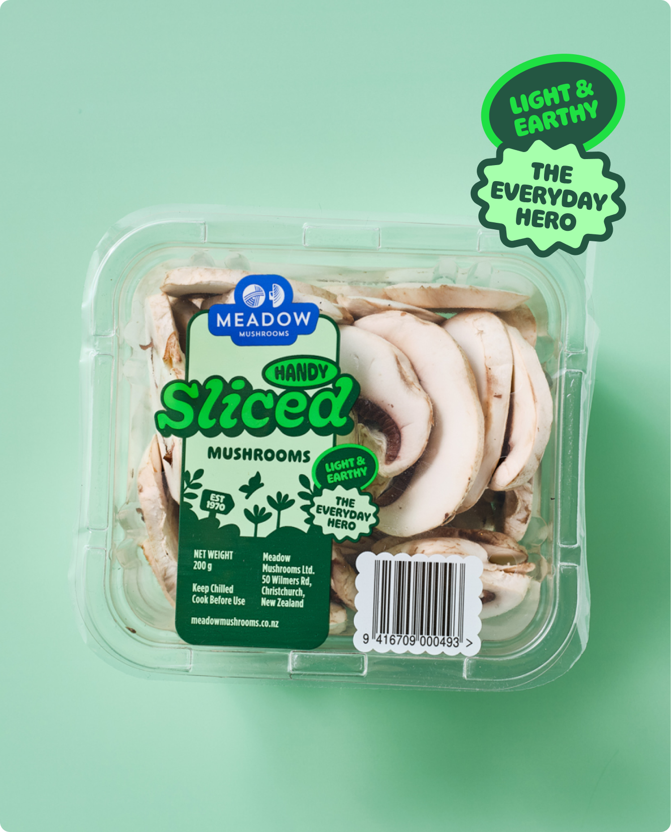 Package of sliced white mushrooms in a clear plastic container with green and blue labels on a light green background.