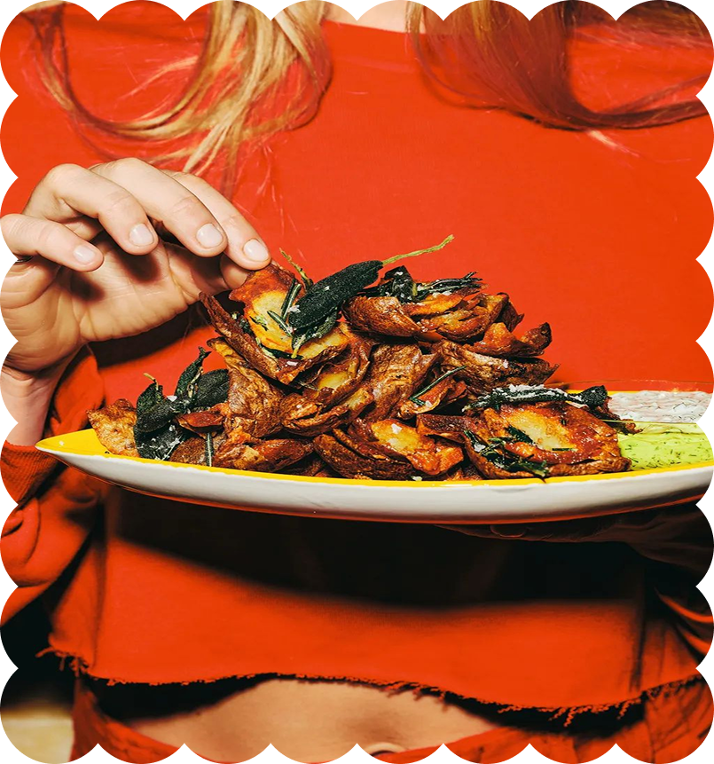 Person in red shirt holding a plate of cooked insects, garnished with greens.