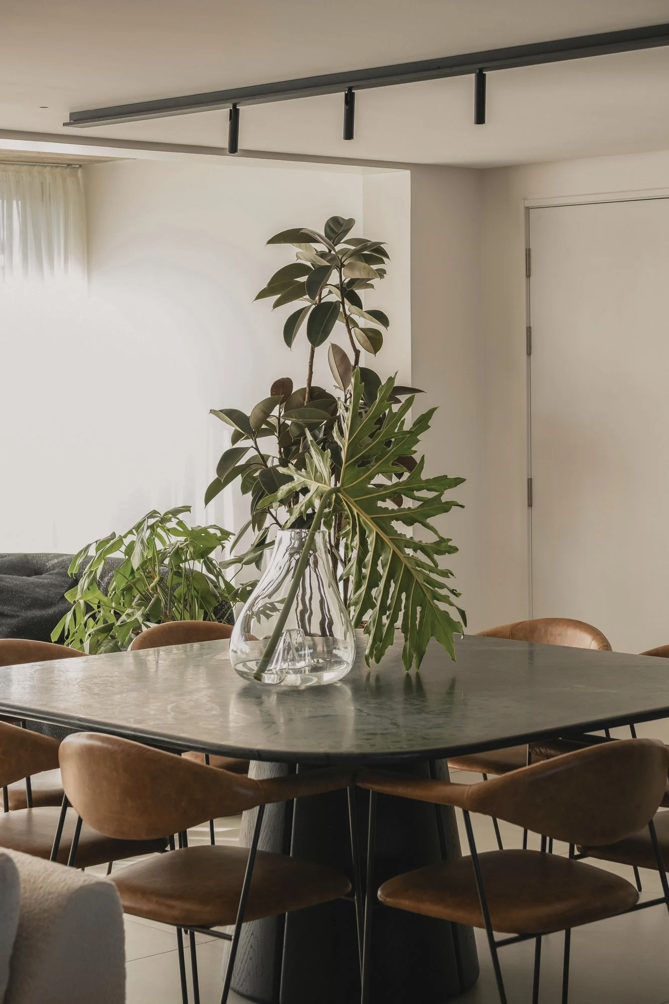 Dining table with chairs and vase near indoor plants