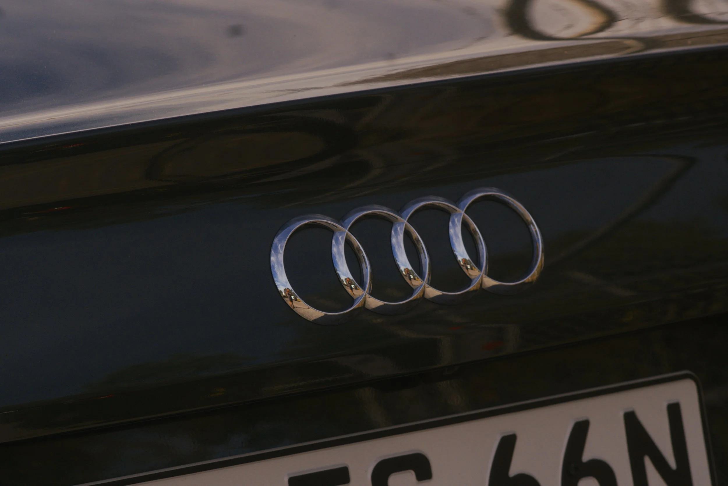 Close-up of an Audi car logo on the front grille of a black vehicle.