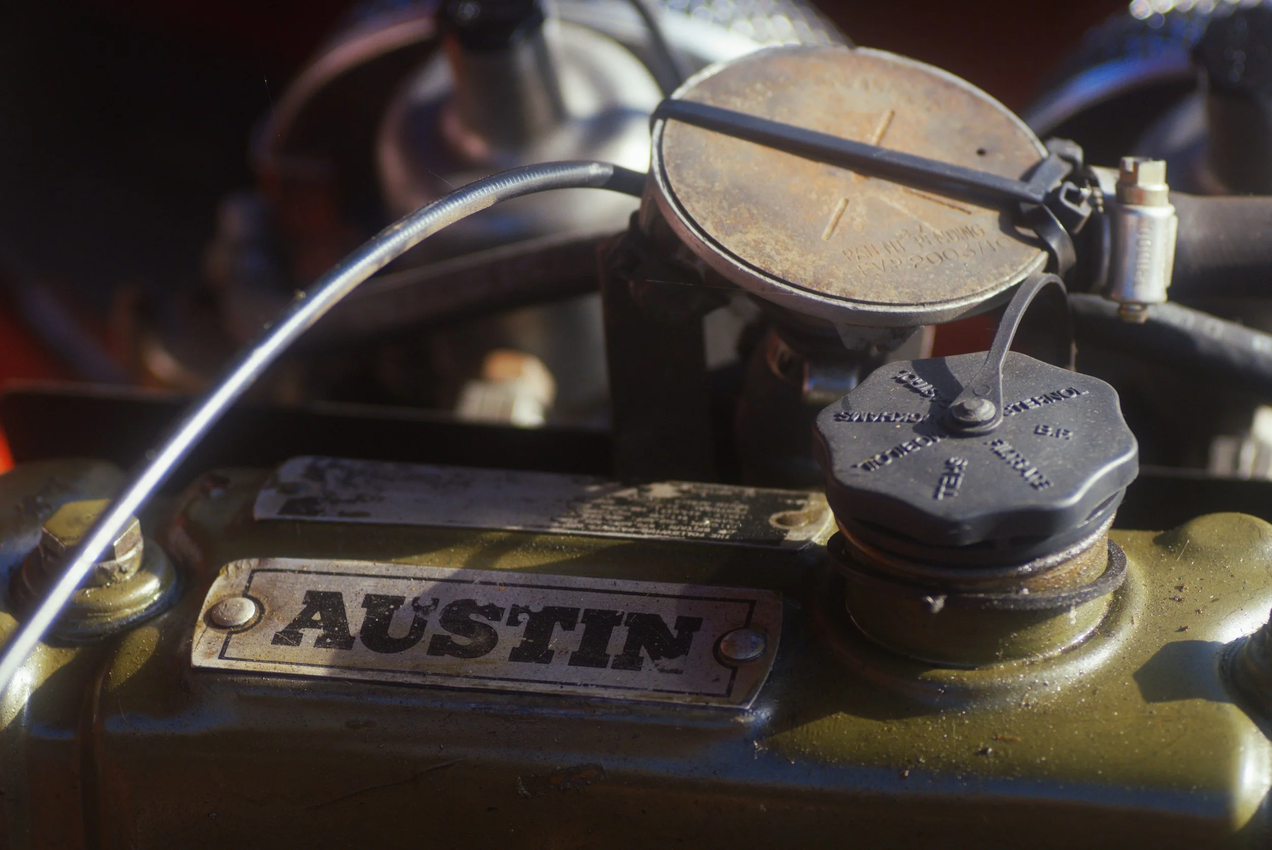 Close-up of a rusty metal car part with a warning label that says 'WARNING' and a radiator cap labeled 'FILL TO'.